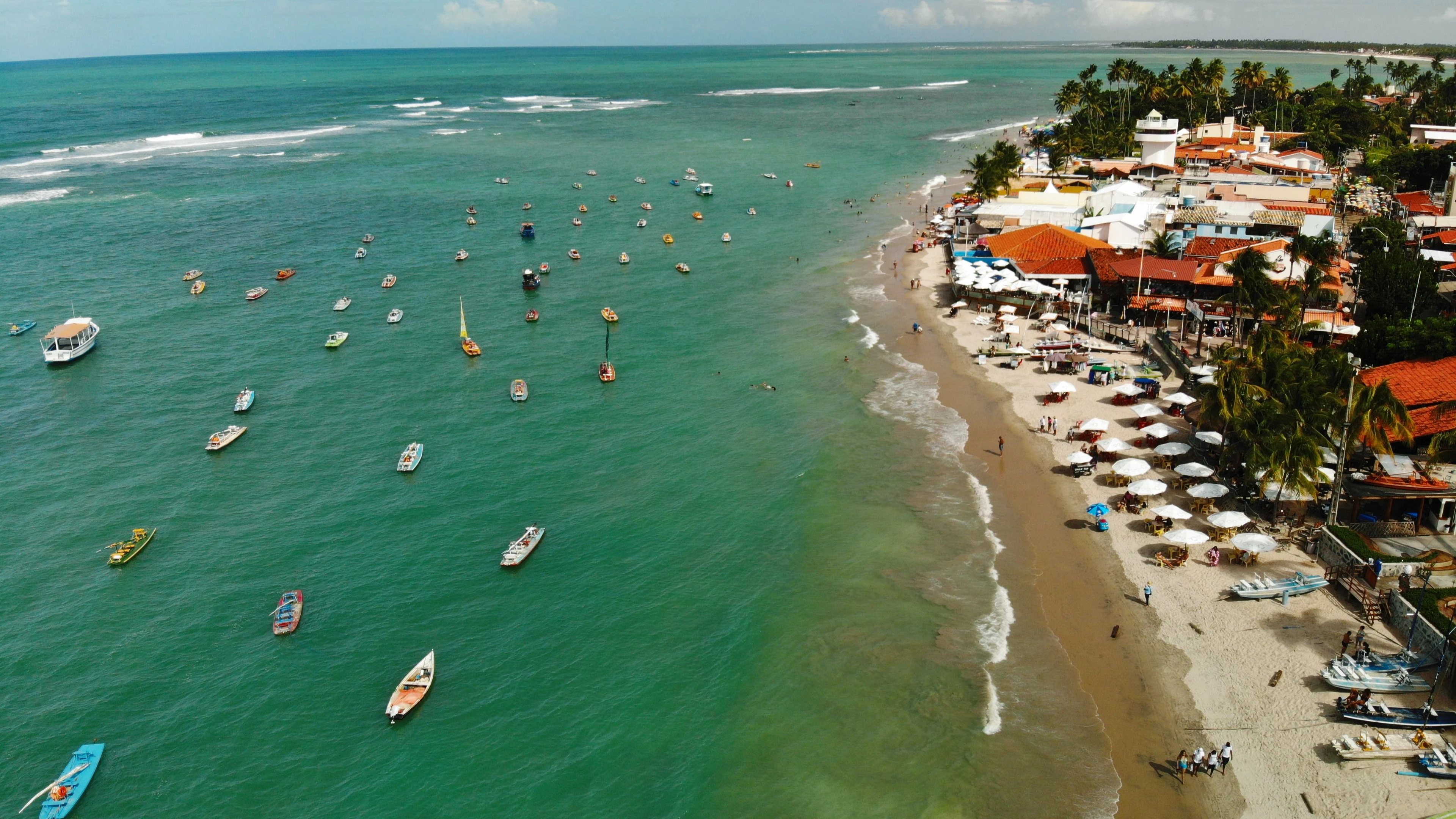 Boats gather along the village waterfront at Porto de Galinhas, seen from above
