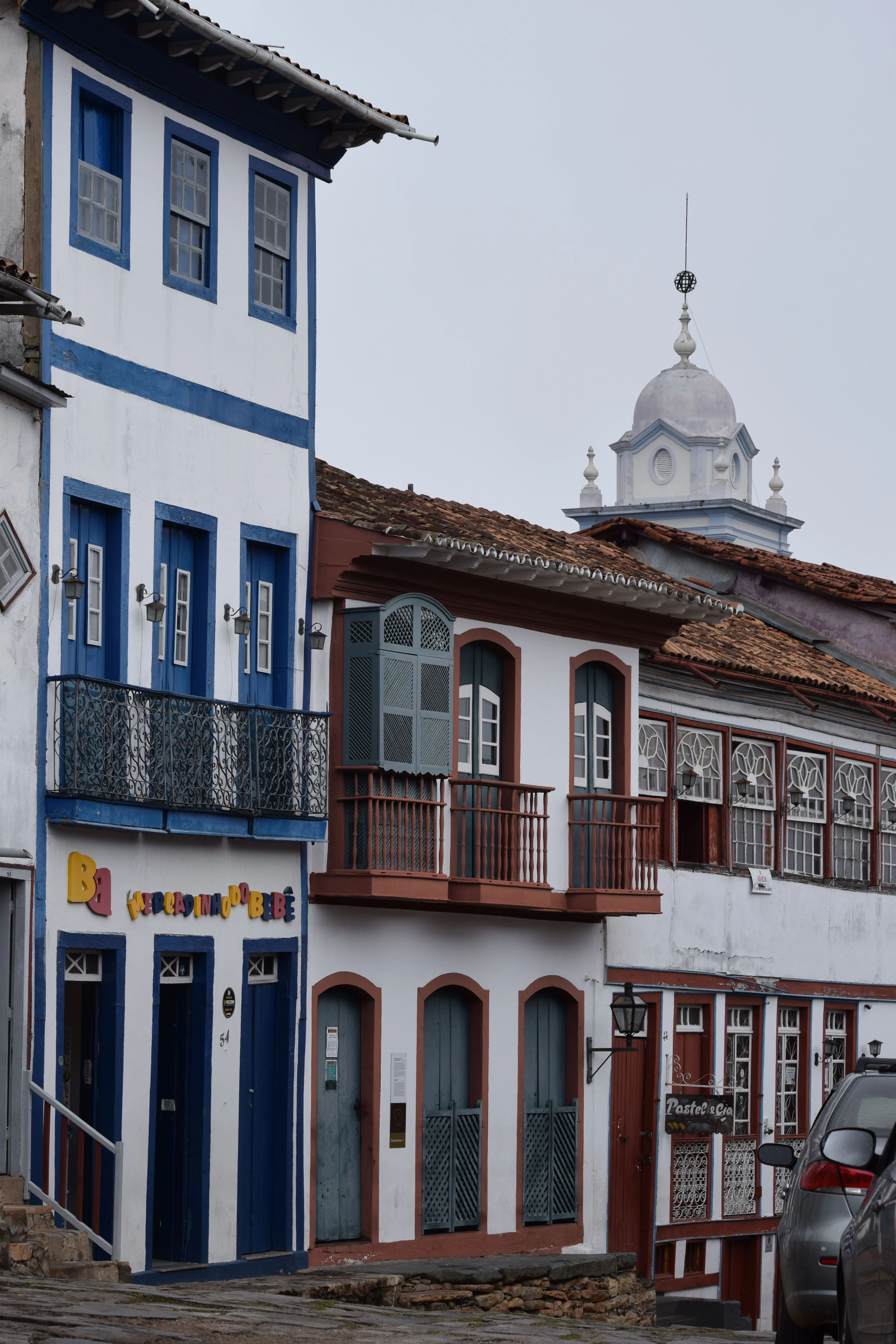 Blue and red balconies line an uneven street in Ouro Preto