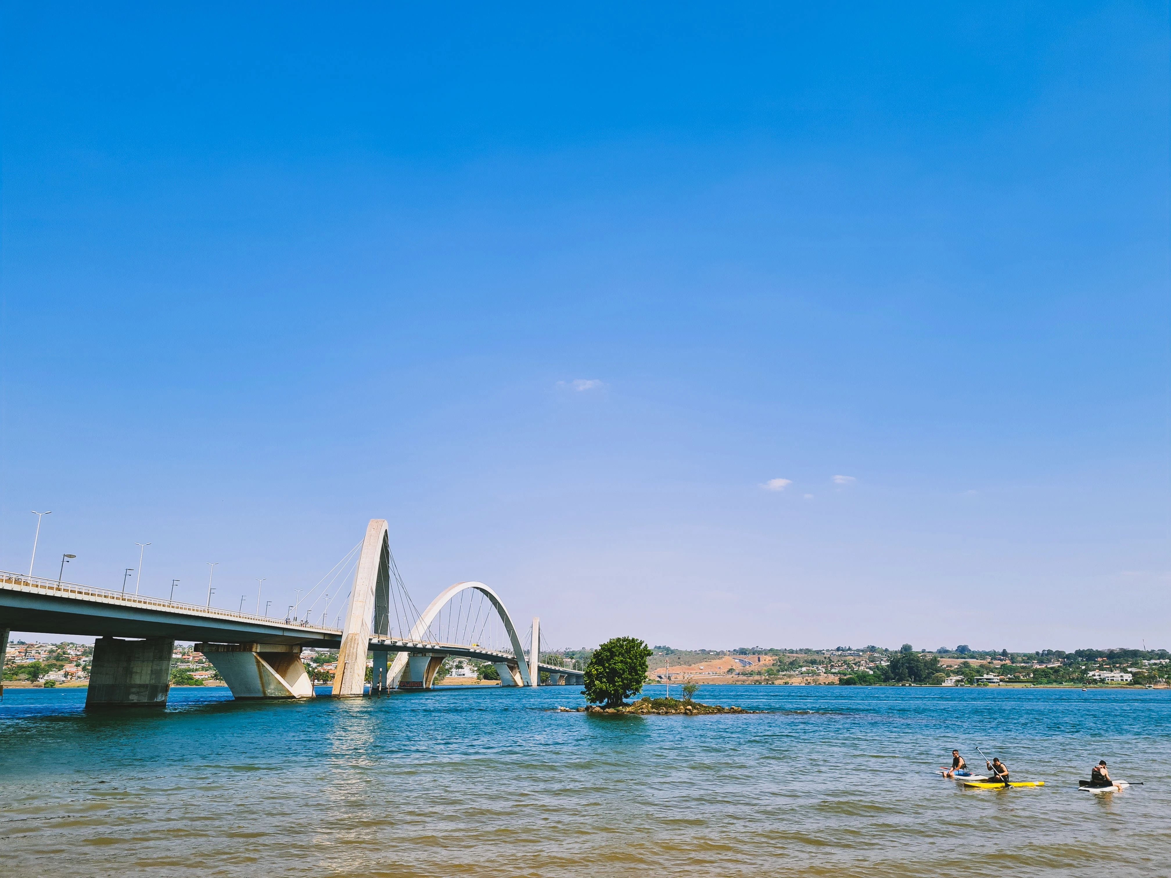 Kayakers on Lake Paranoá beneath the curved arches of Brasília's JK Bridge.