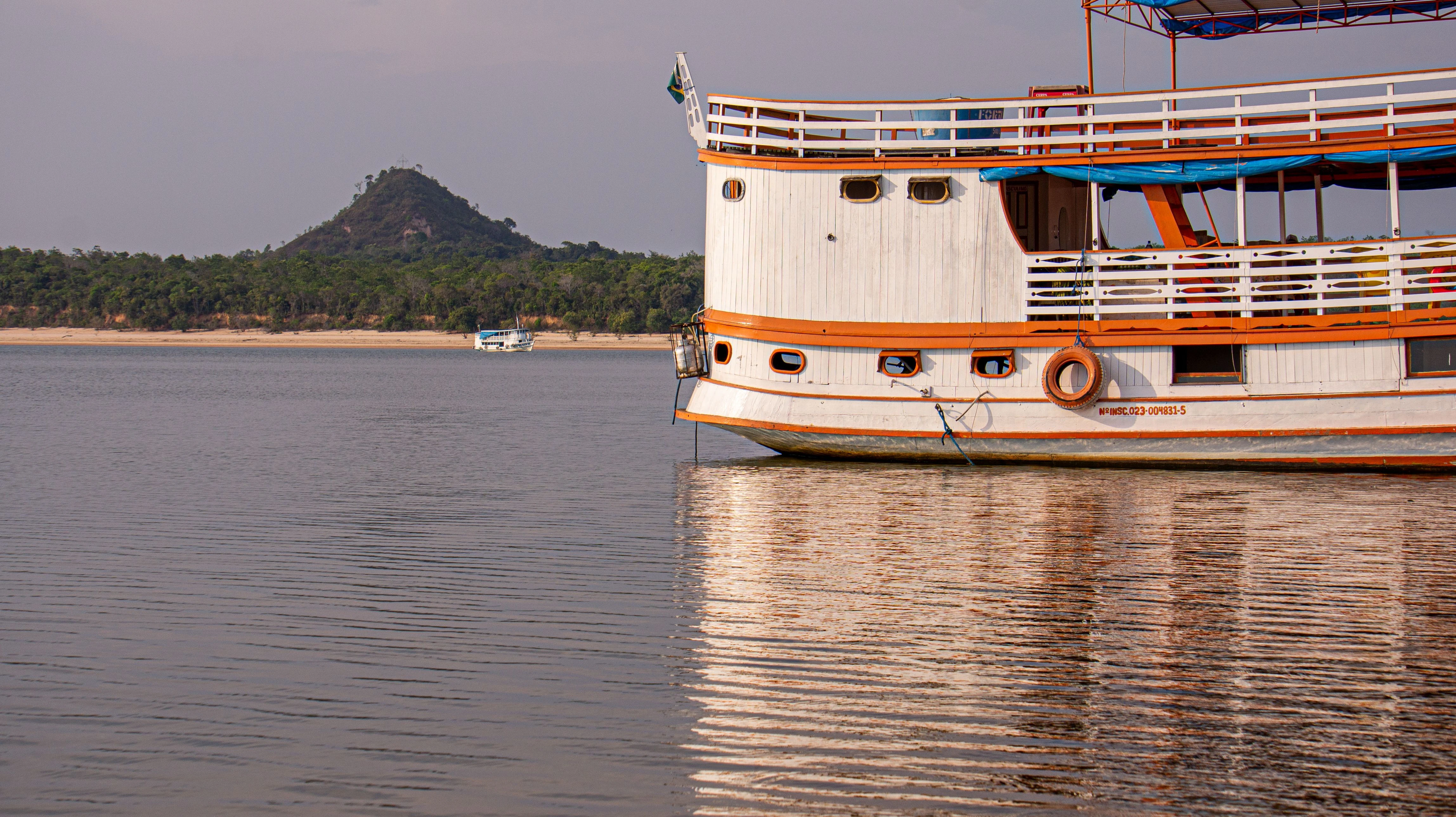 Orange and white riverboat beside the Tapajós shoreline in Pará