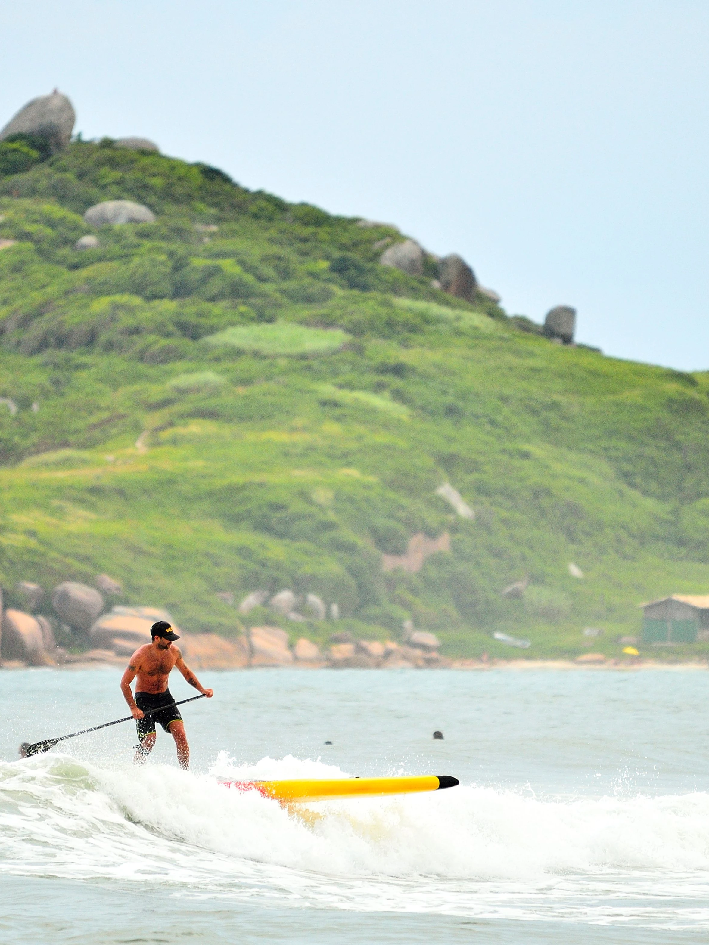 A stand-up paddler moves across the water at Barra da Lagoa, Florianópolis.