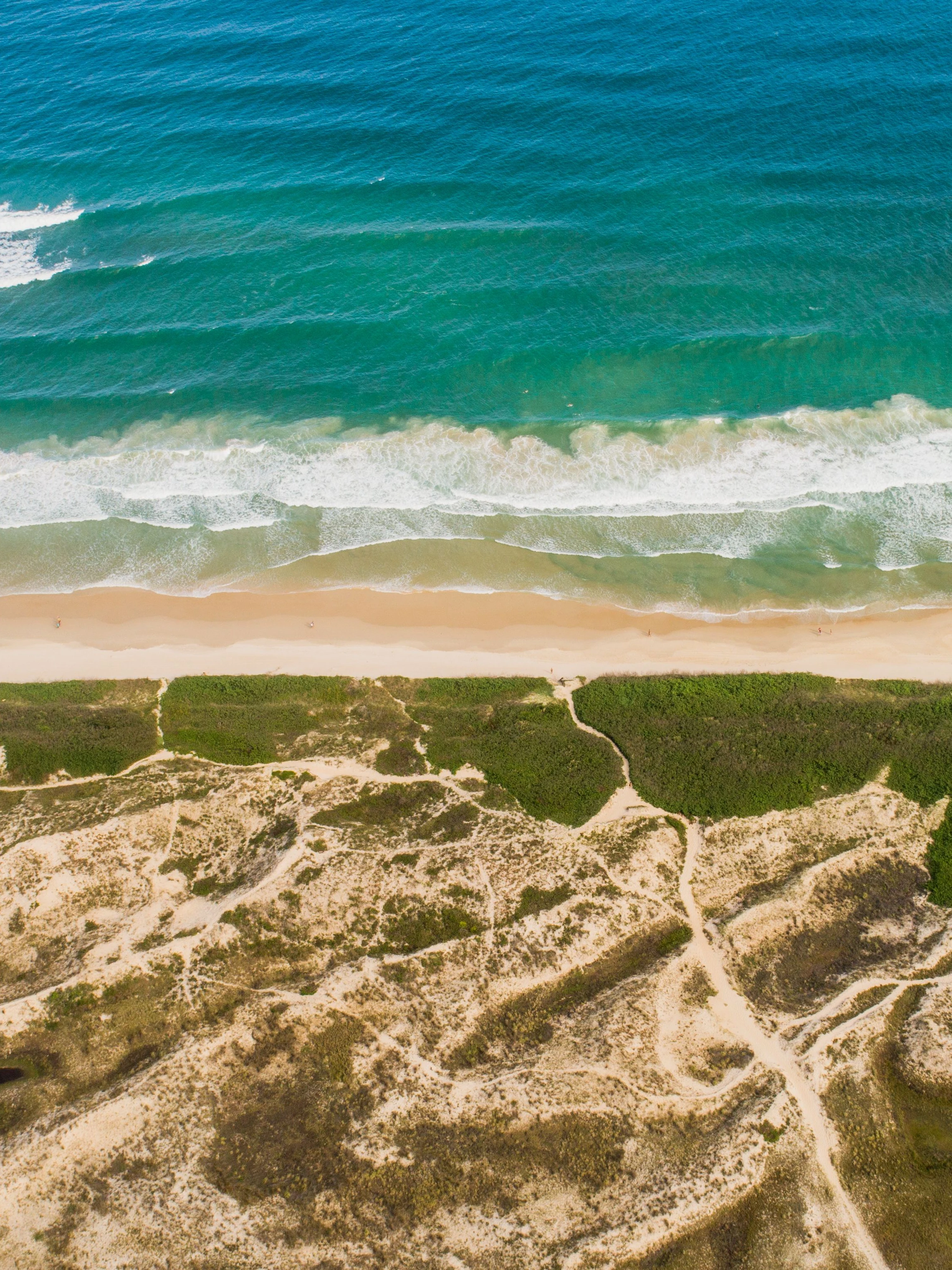 Dunes and surf seen from overhead along the Florianópolis coast.