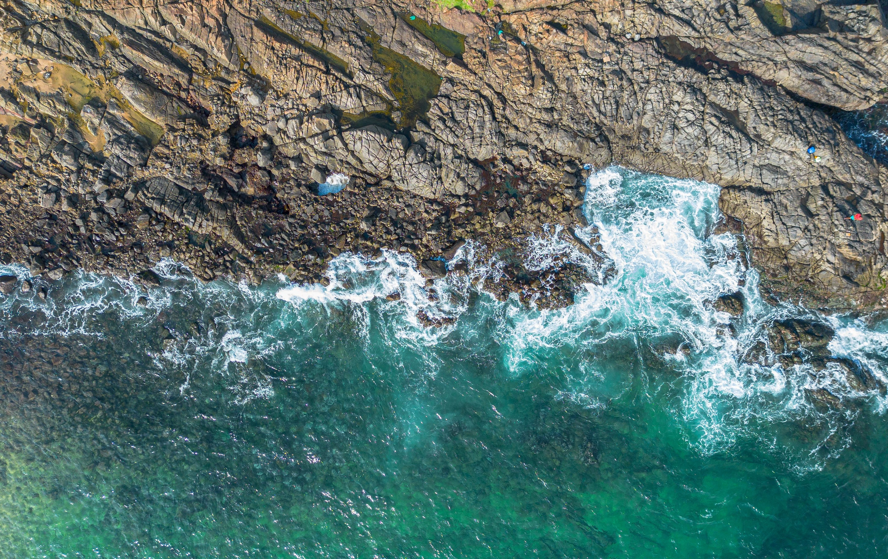 Stunning aerial view capturing crashing waves on rocky coast in Salvador, Brazil. Ideal for travel and nature themes.