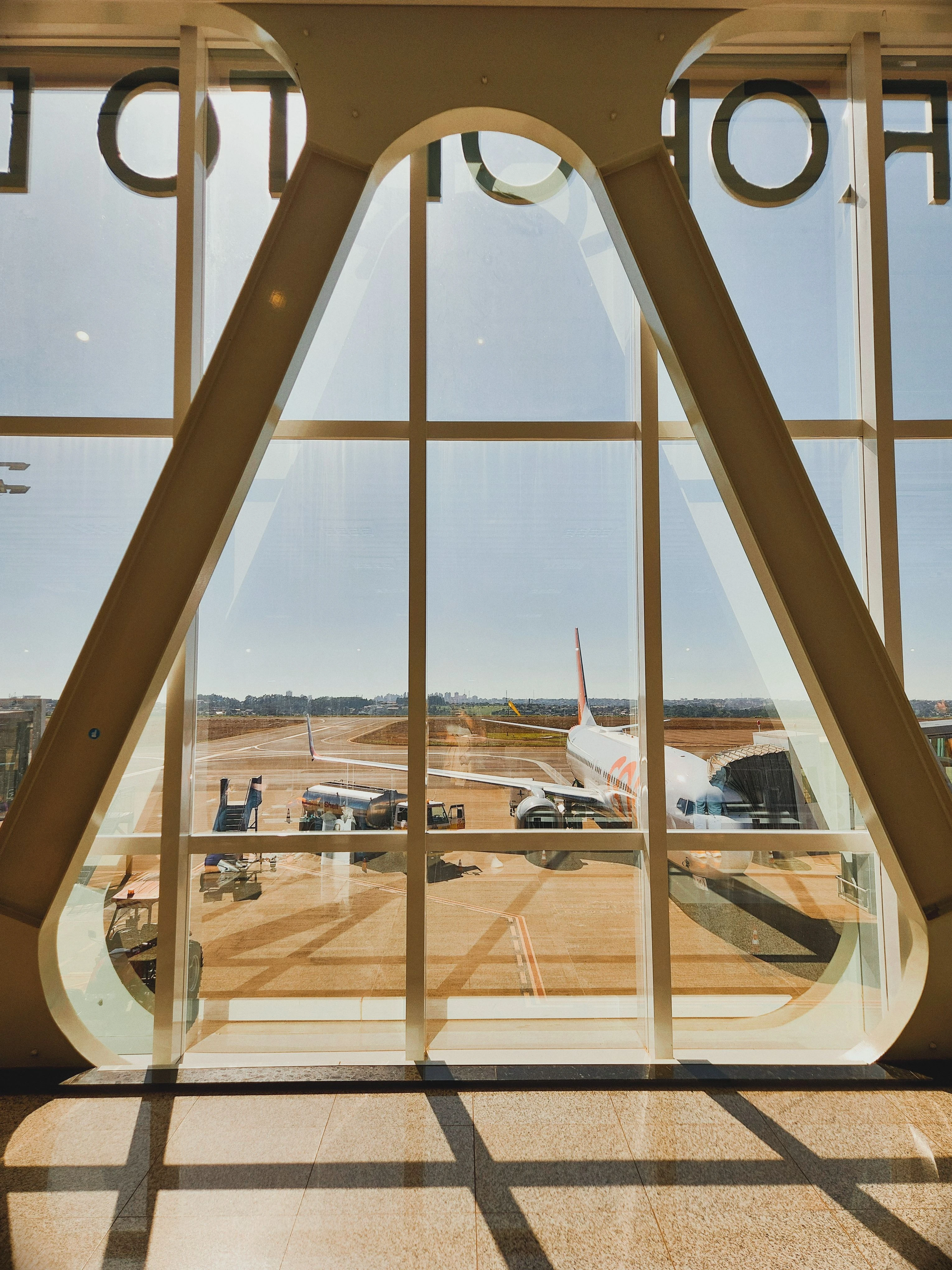 An airliner framed by angular terminal windows at Cascavel airport