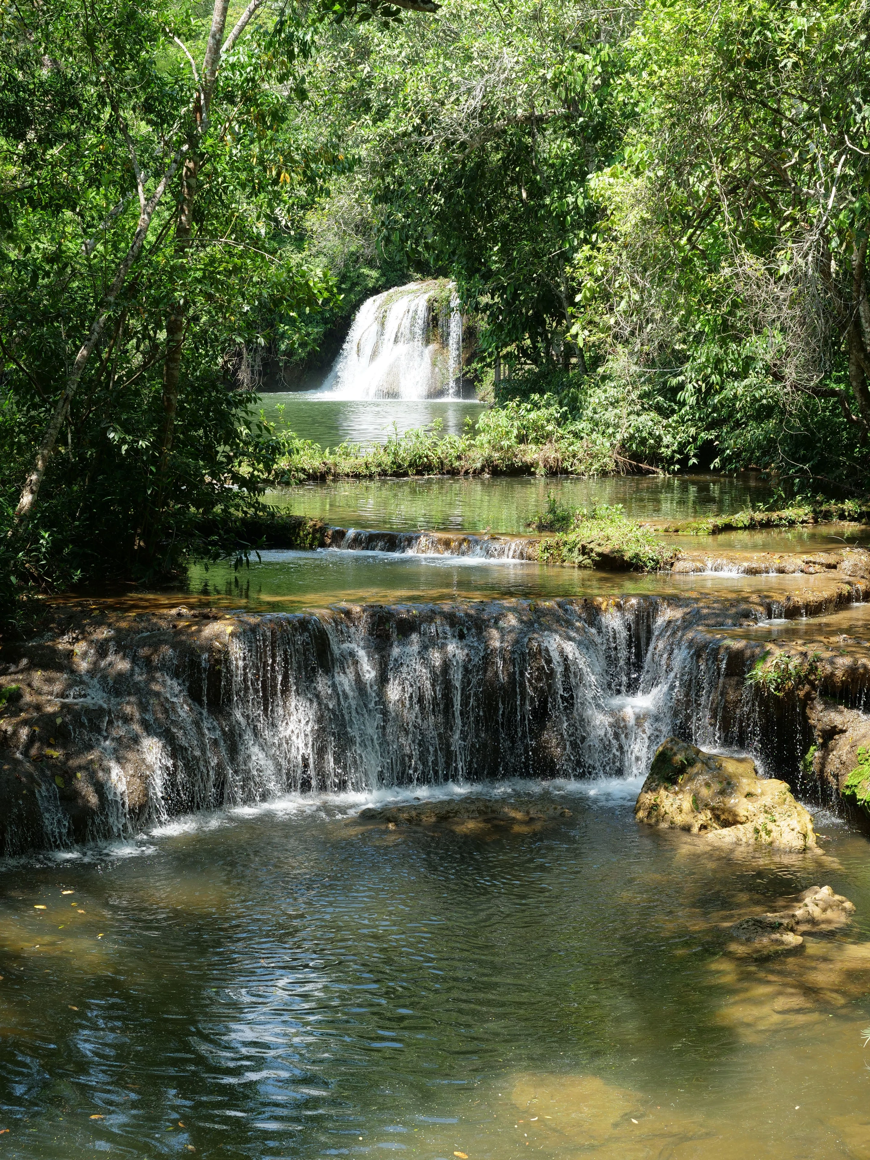 Clear water tumbles over layered cascades surrounded by forest at Bonito, Brazil