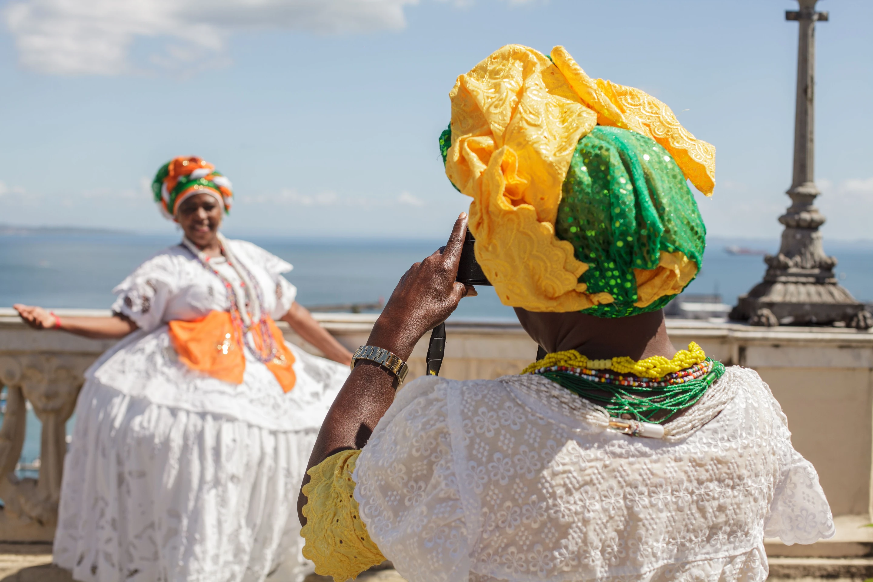 Women in colorful Bahian dress take photographs together in Salvador