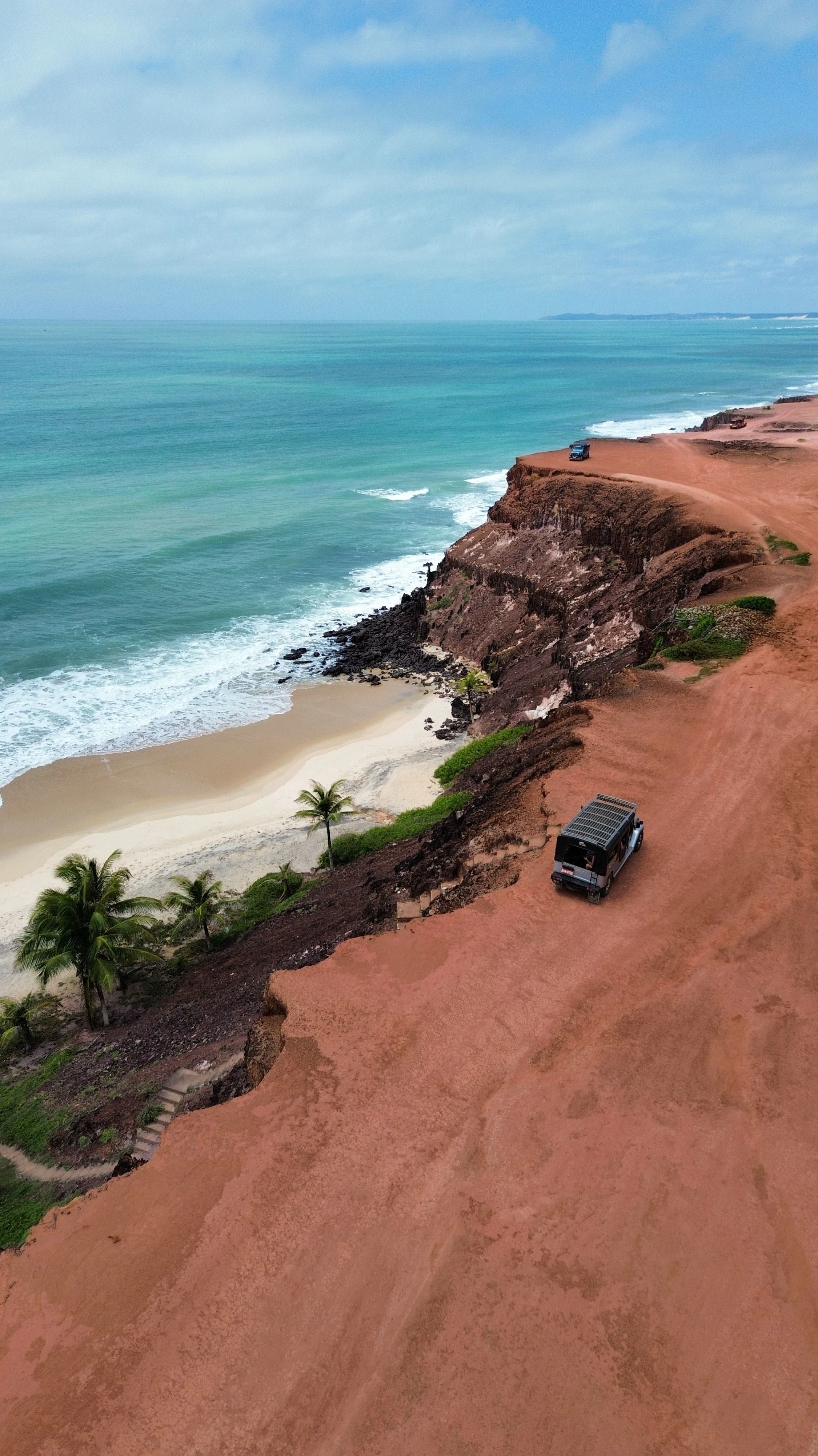 A coastal track above orange cliffs and turquoise water at Pipa