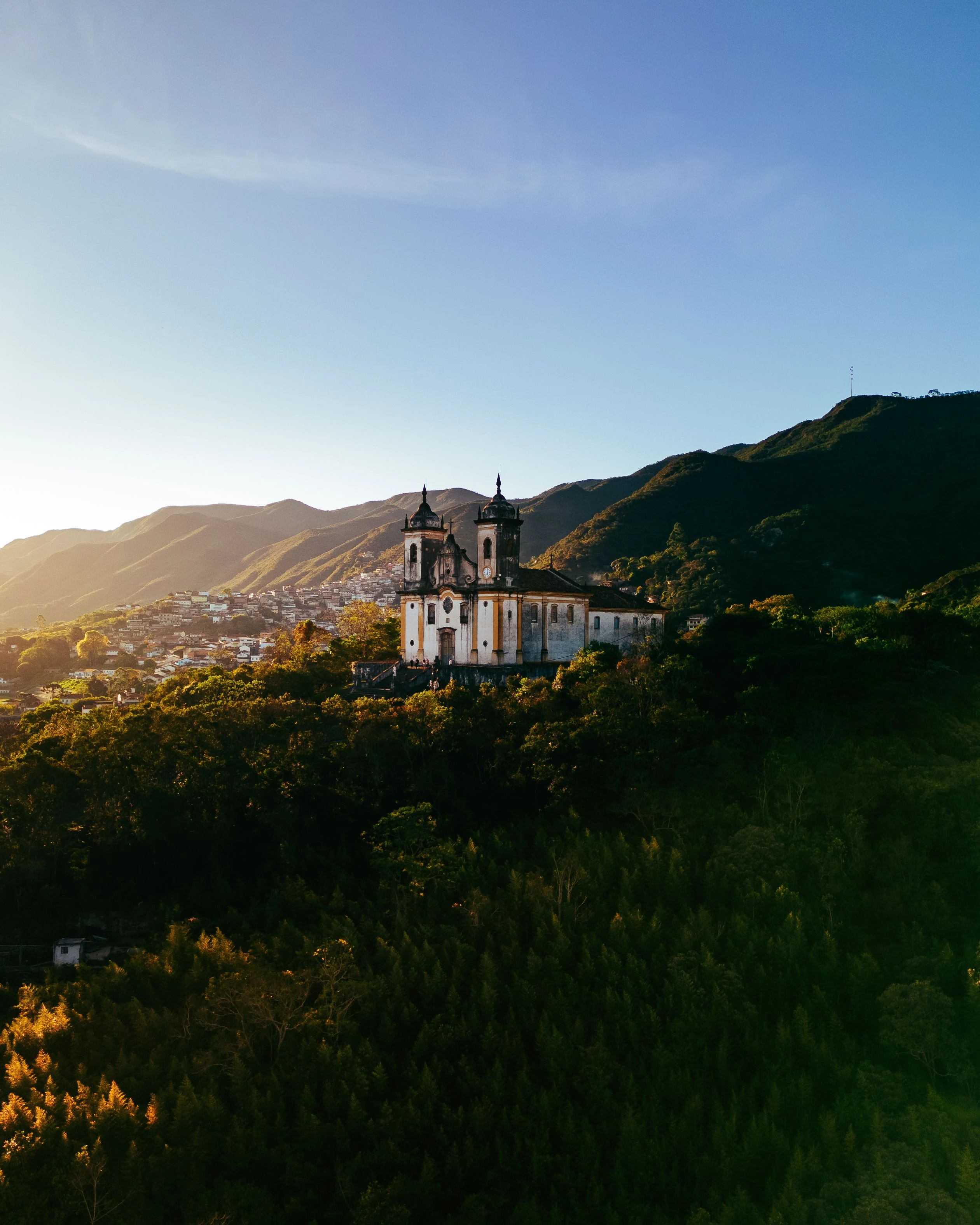 A sunlit historic church above the hills and tiled roofs of Ouro Preto