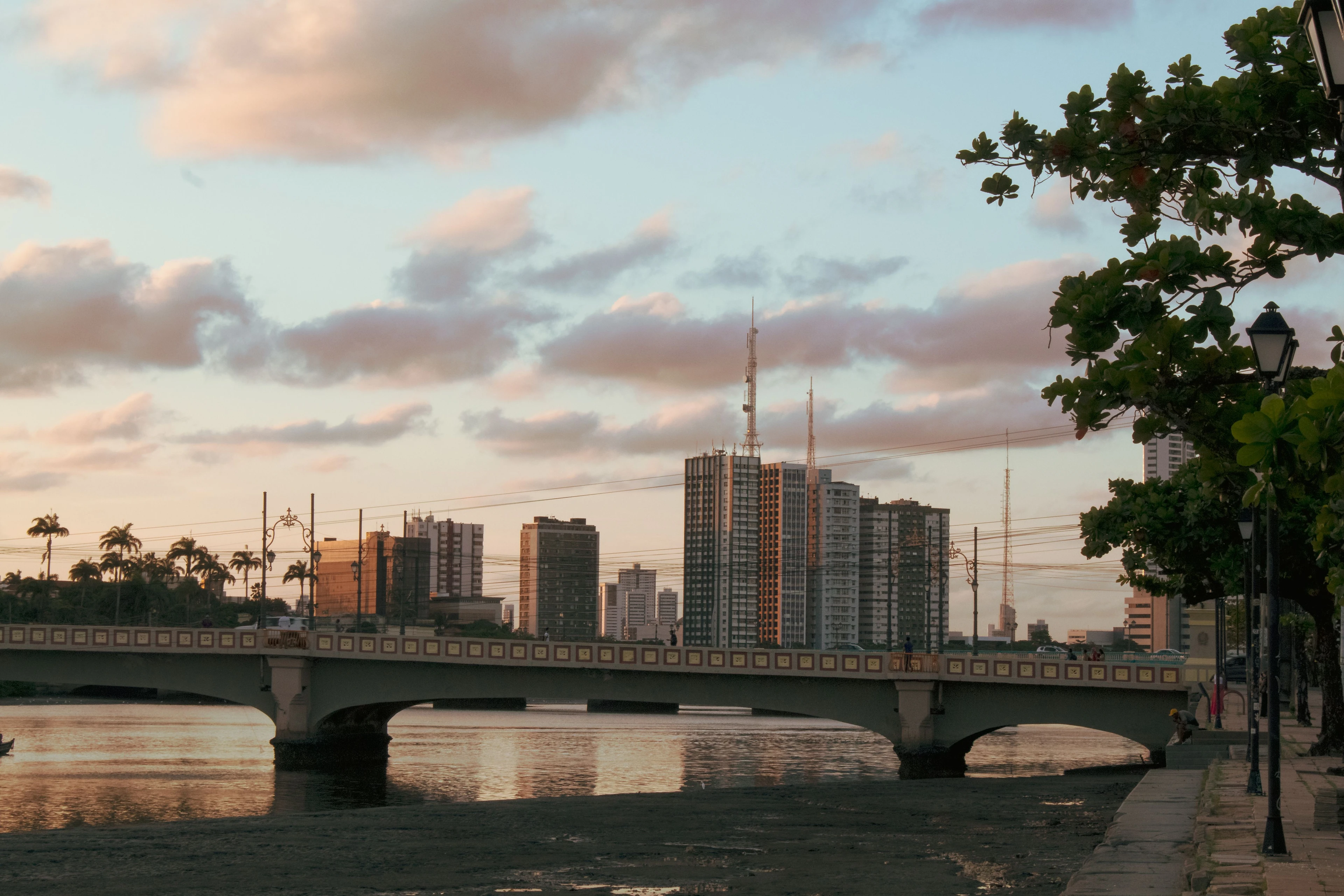 Warm evening light across a river, bridge and city buildings in Recife