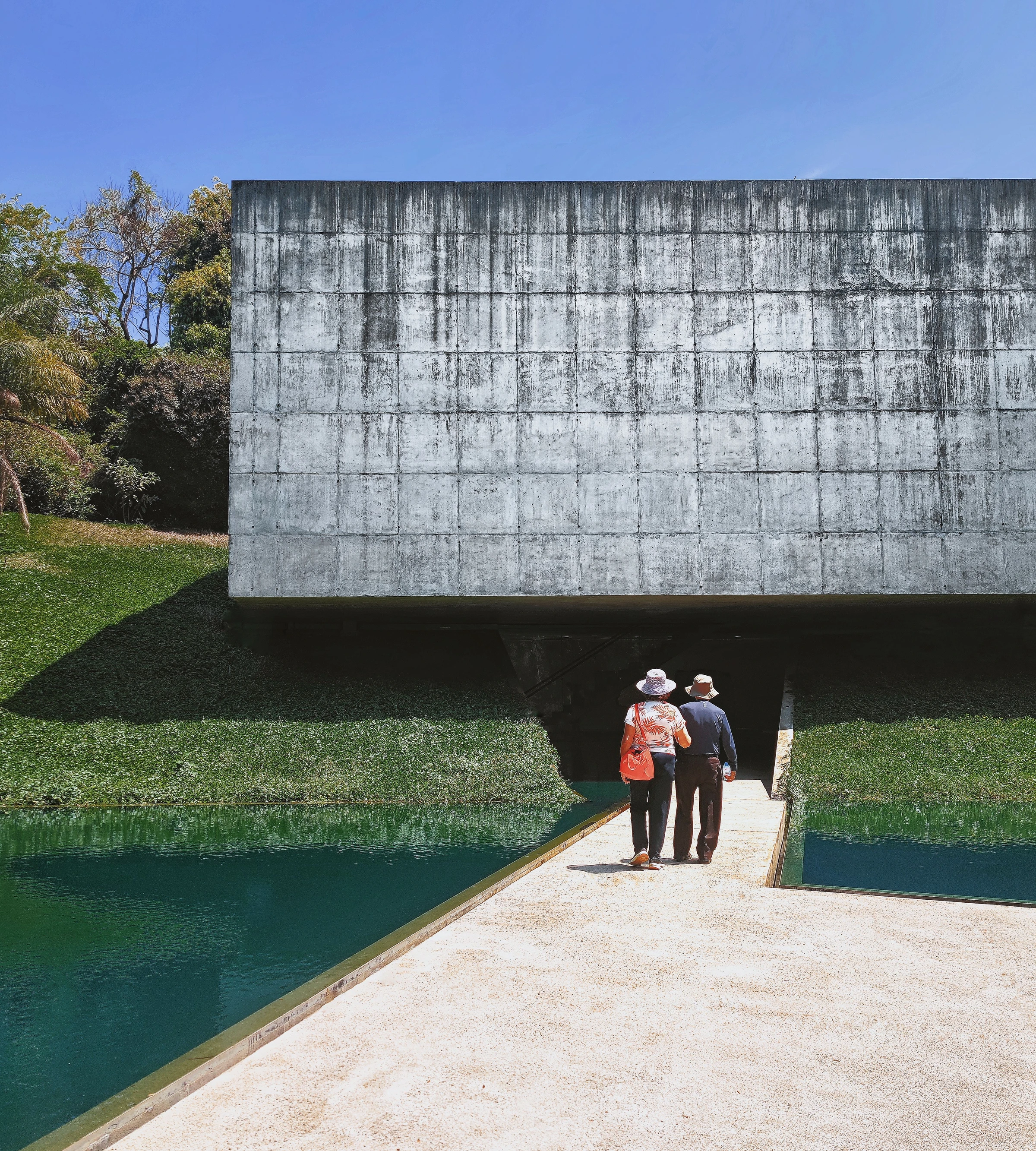 Two visitors walk towards the Adriana Varejão Gallery at Inhotim.