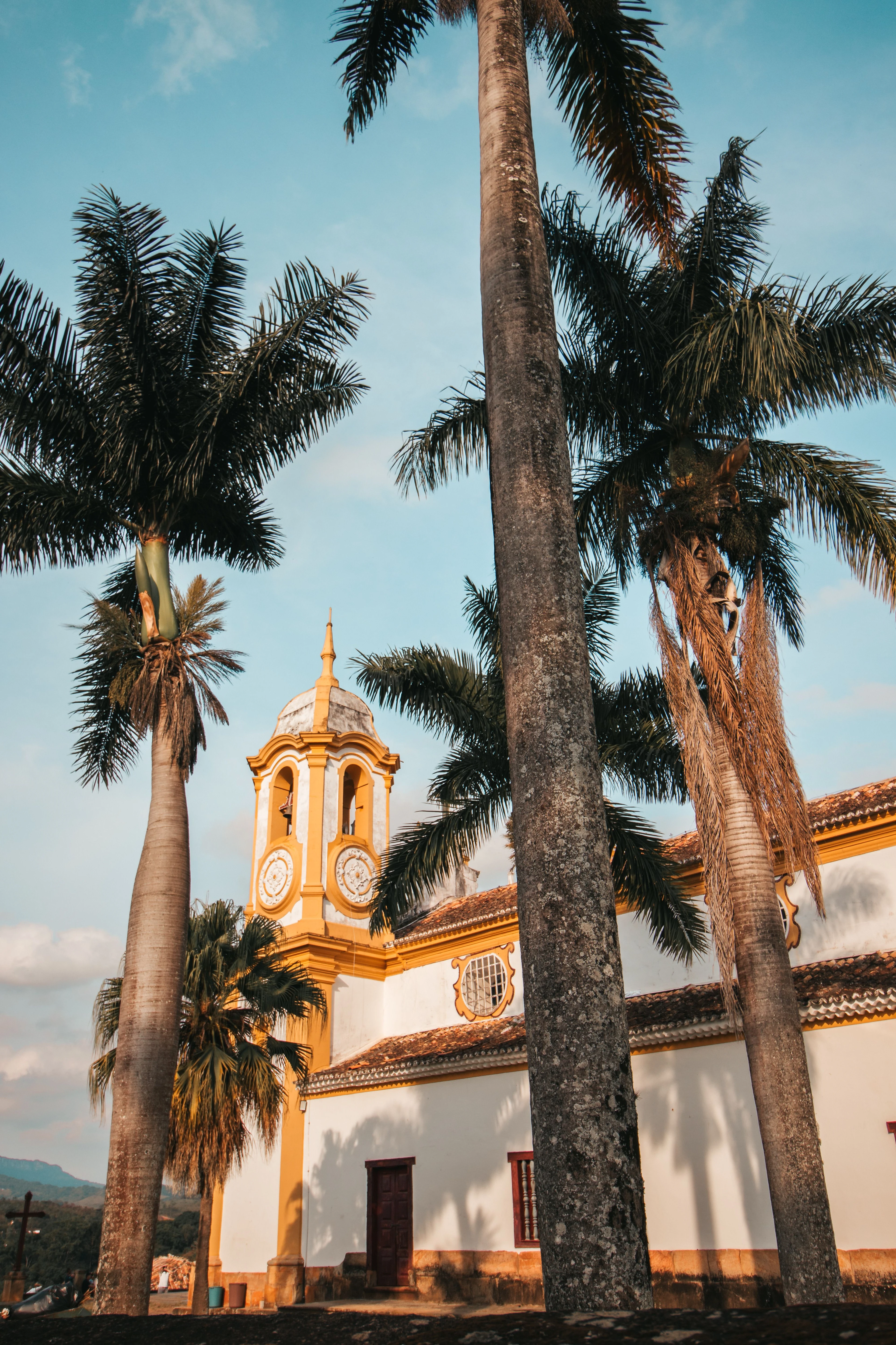Warm sunlight reaches Santo Antônio church between palms in Tiradentes