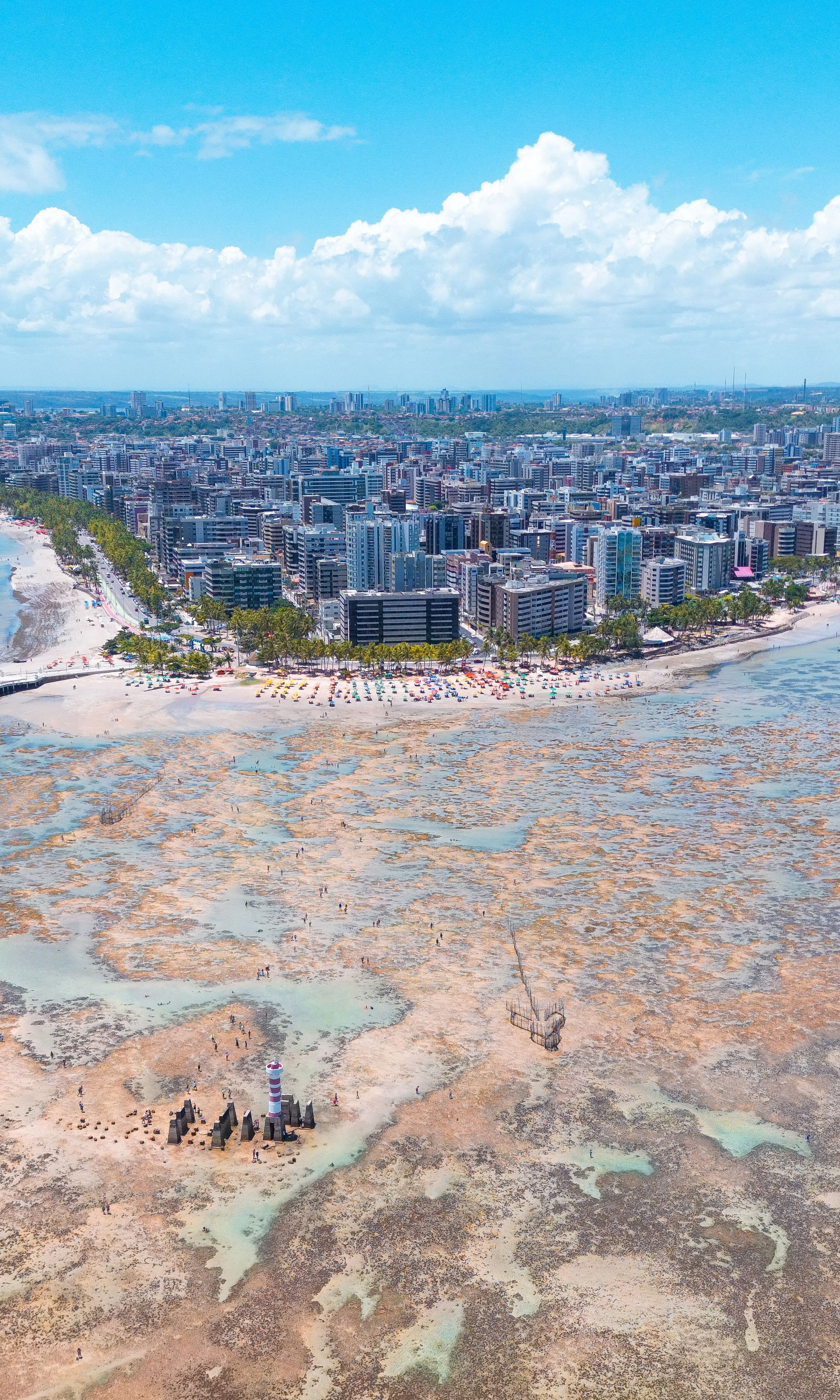 An aerial view shows Maceió’s city blocks, coastline and exposed reef patterns.
