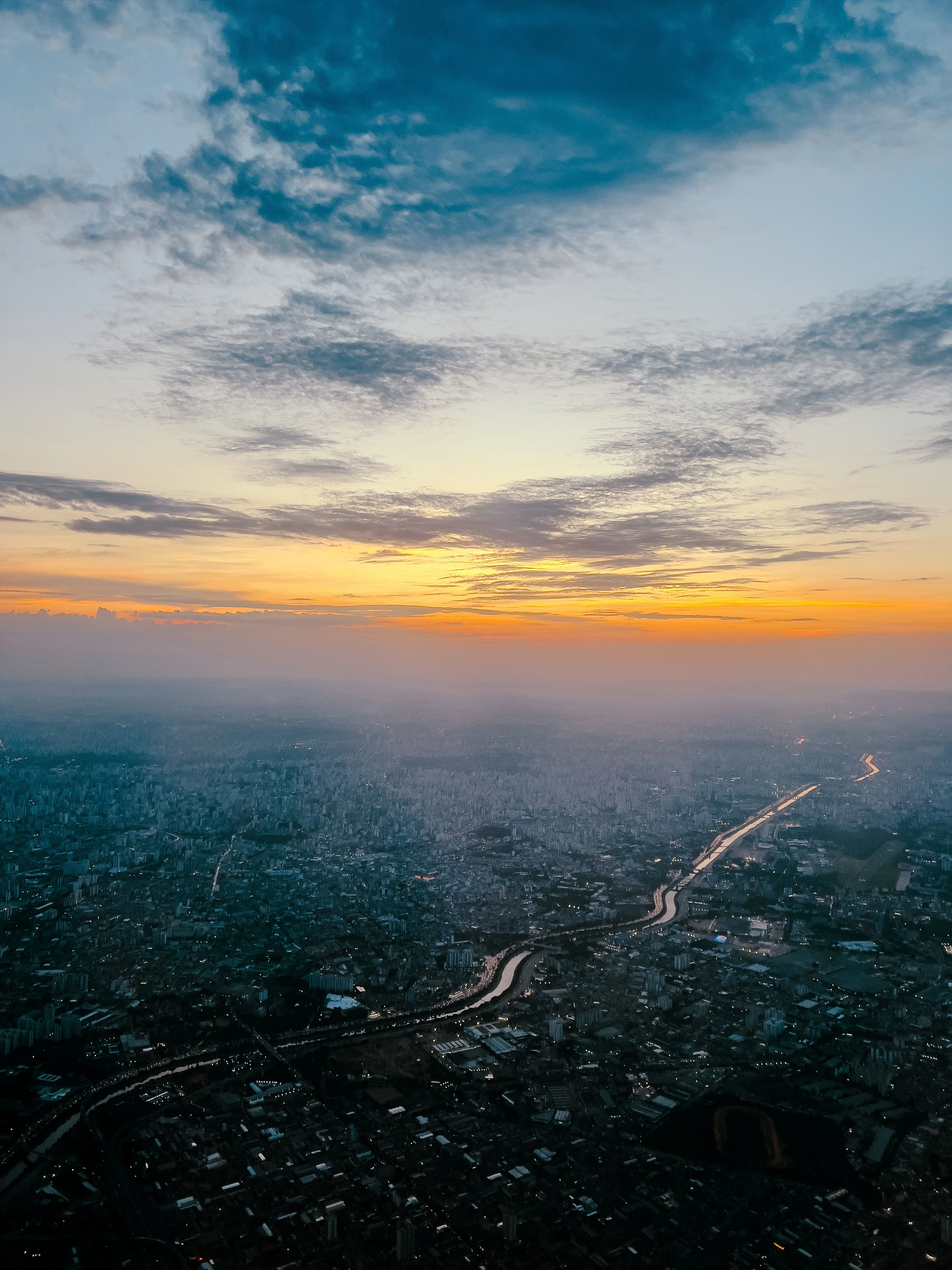 The immense São Paulo cityscape beneath an orange evening sky