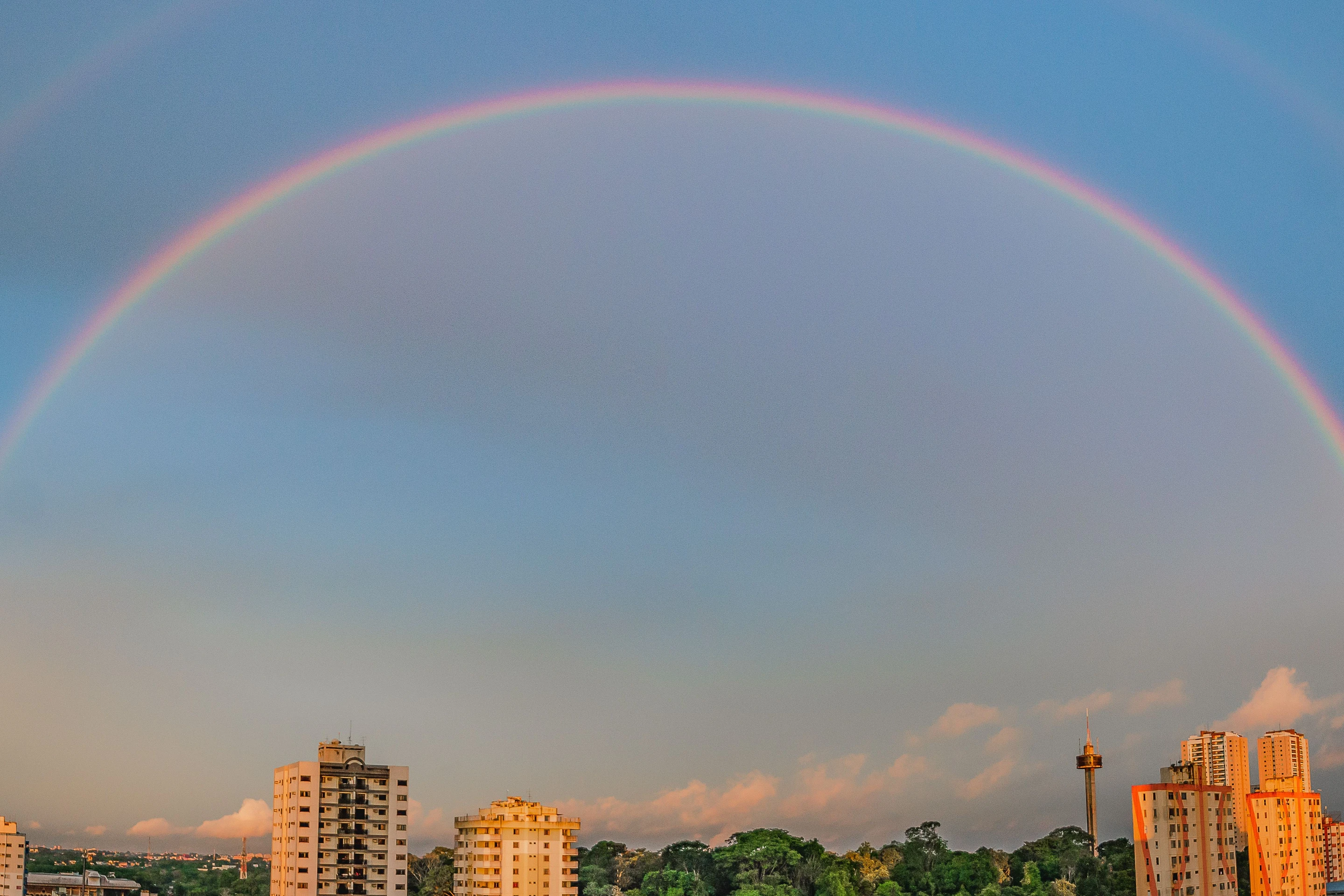 A broad rainbow arcs over sunlit buildings in Belém.