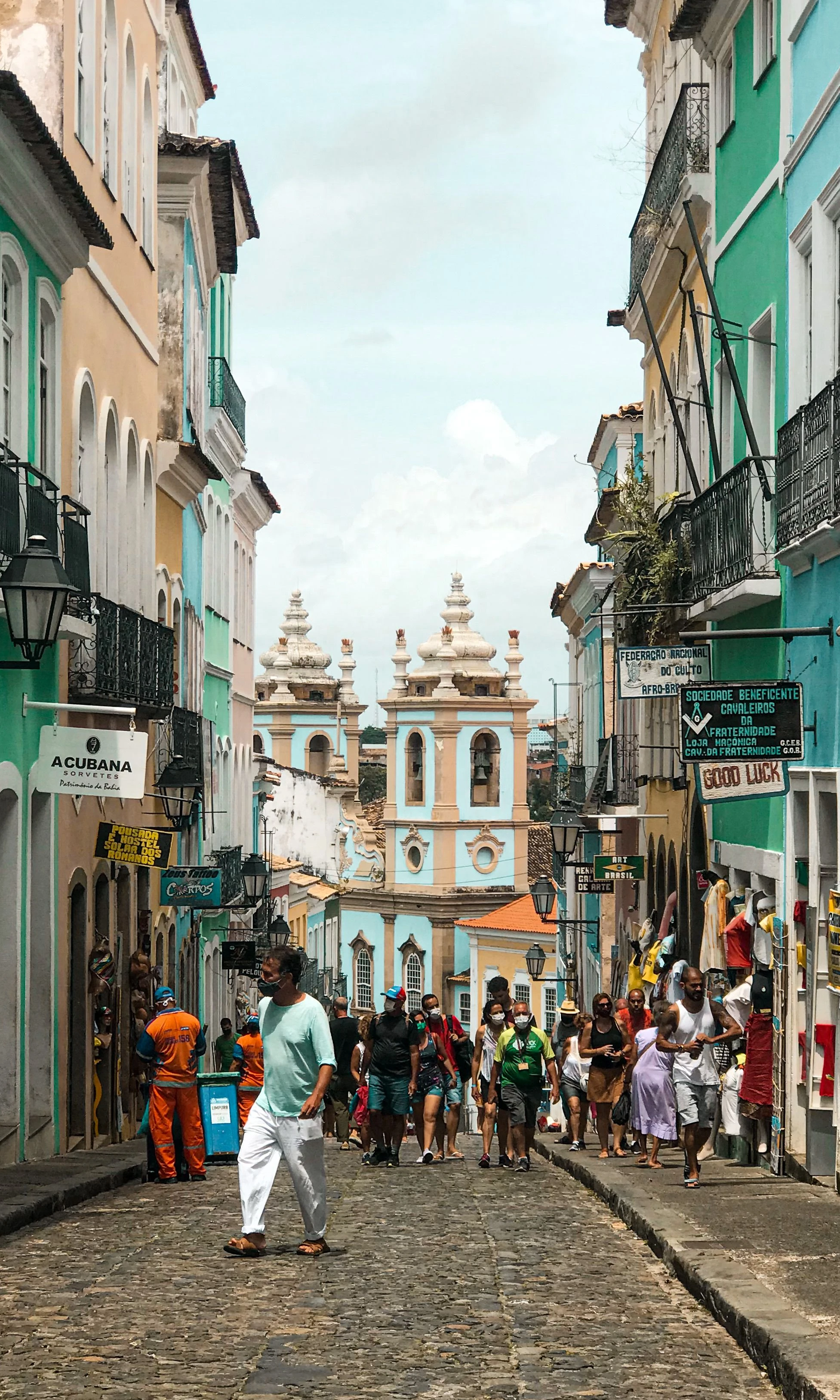 A lively Salvador street leads between colorful façades toward a historic church.