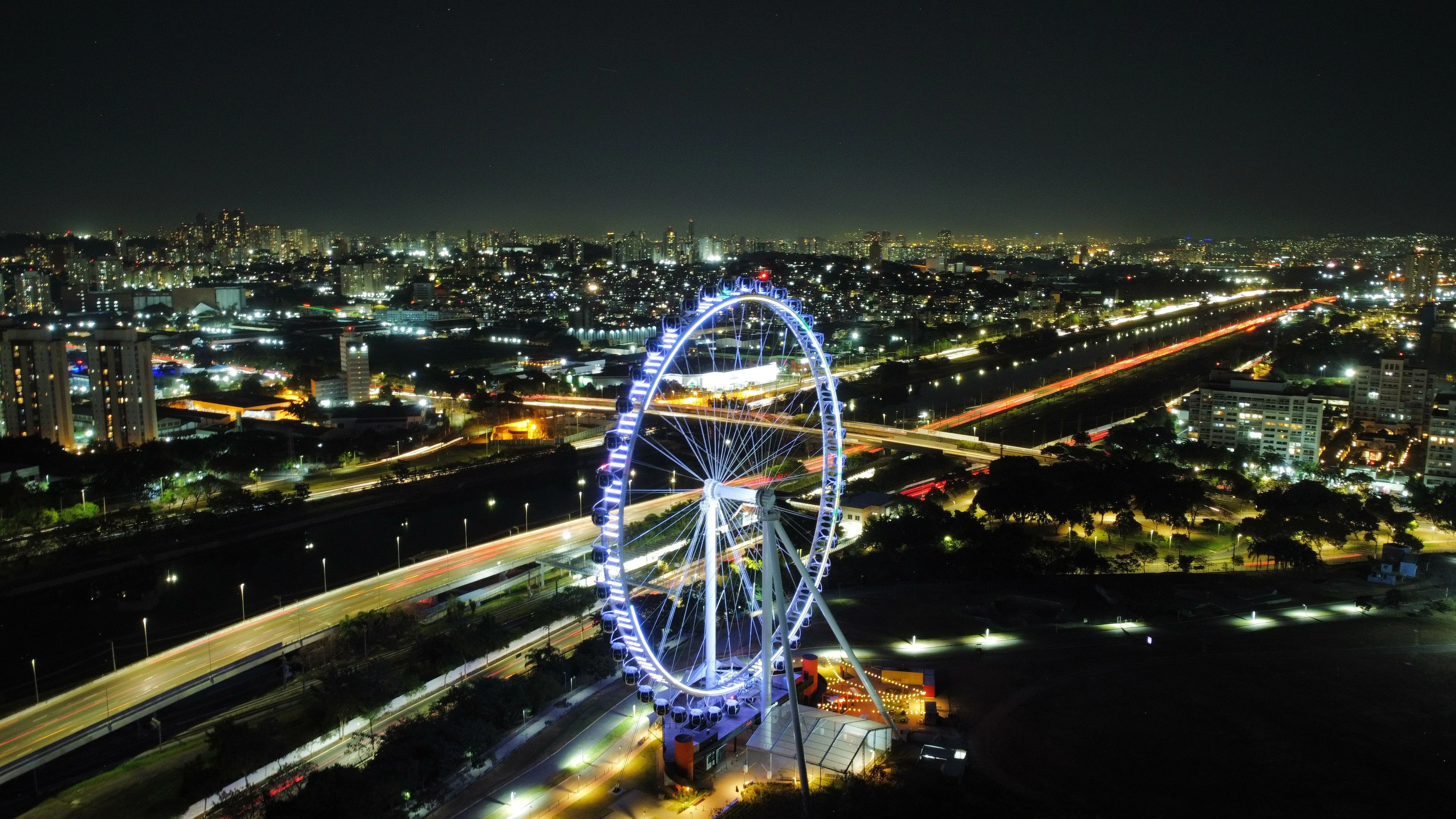 Roda Rico illuminated above São Paulo roads and city lights at night