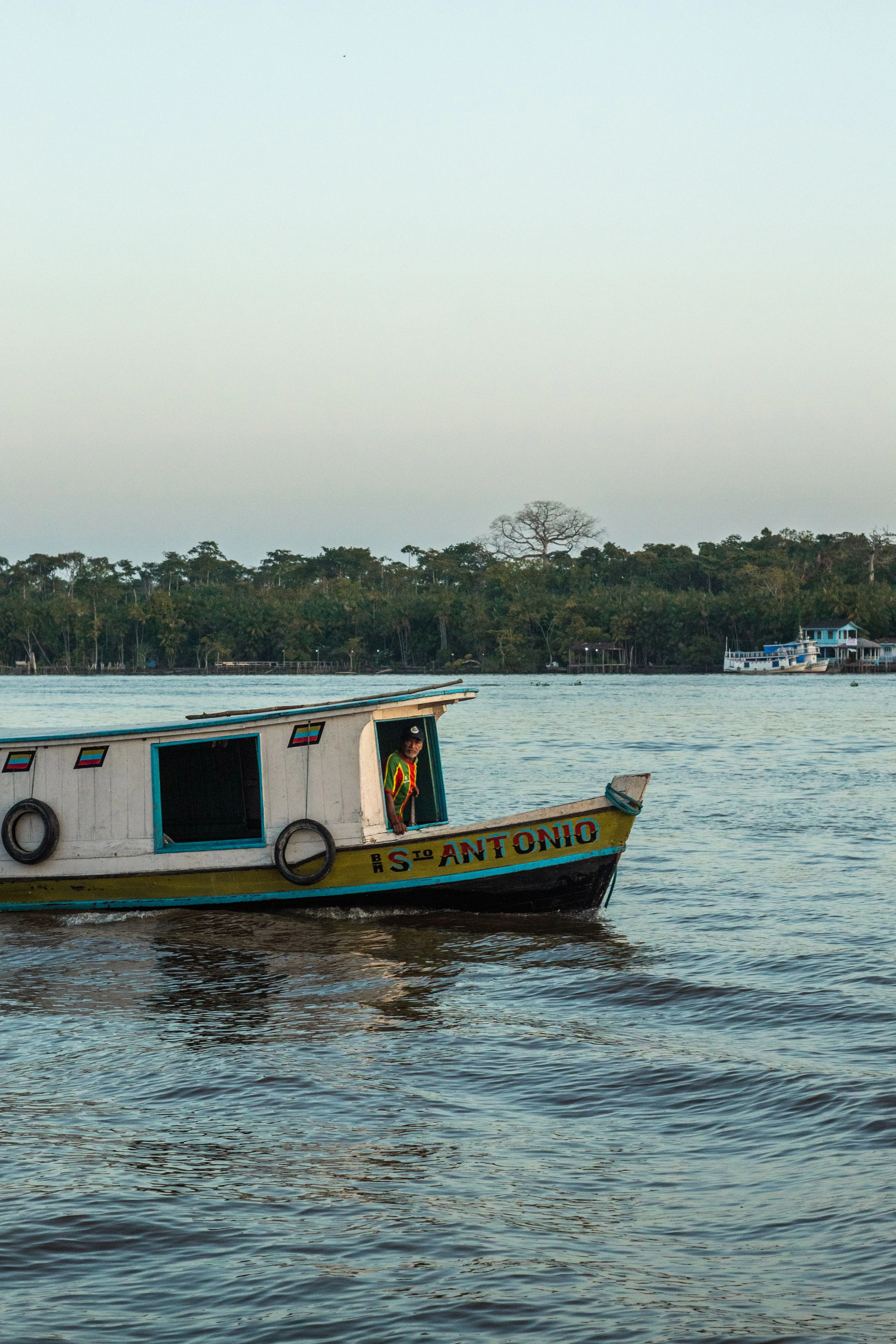 A boatman and painted wooden vessel on the water at Breves in the Marajó region