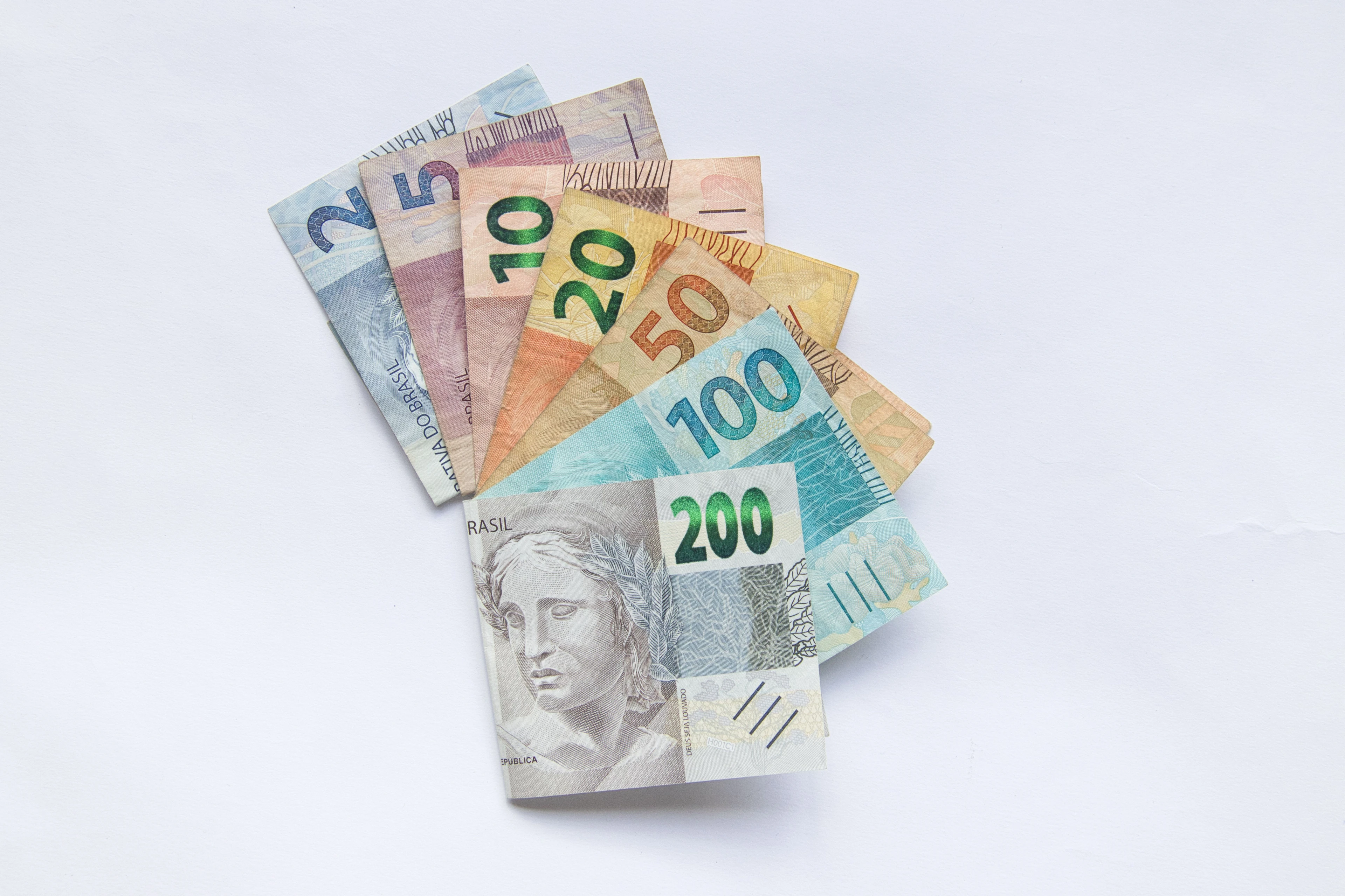 A fan of Brazilian real banknotes displays several denominations