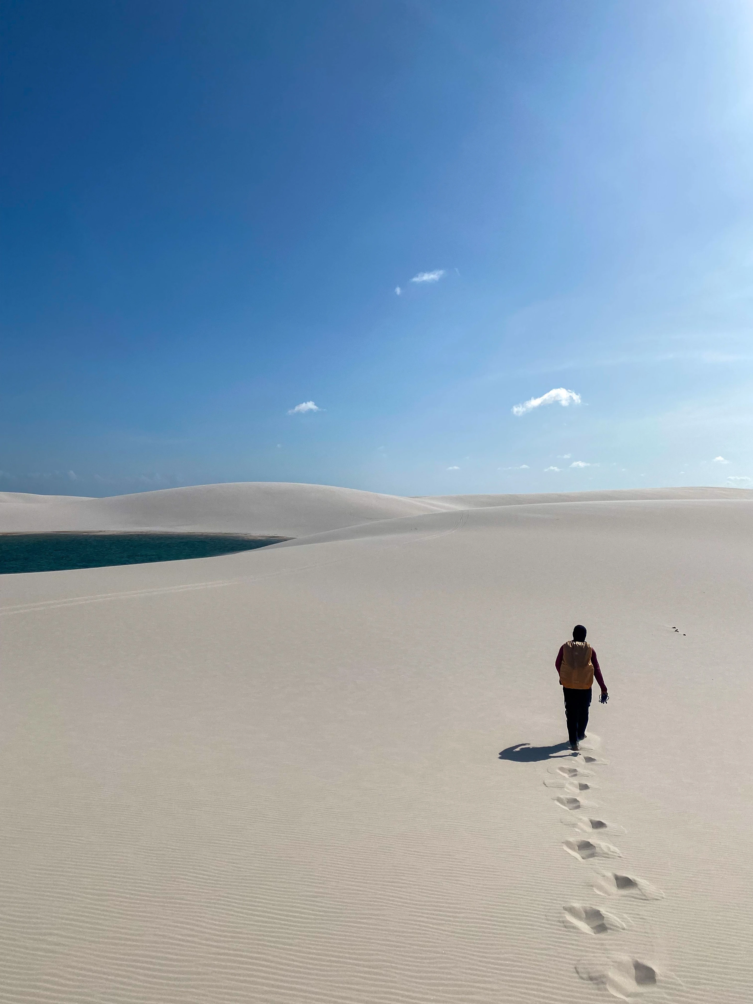 A traveler and footprints show the scale of pale dunes at Lençóis Maranhenses