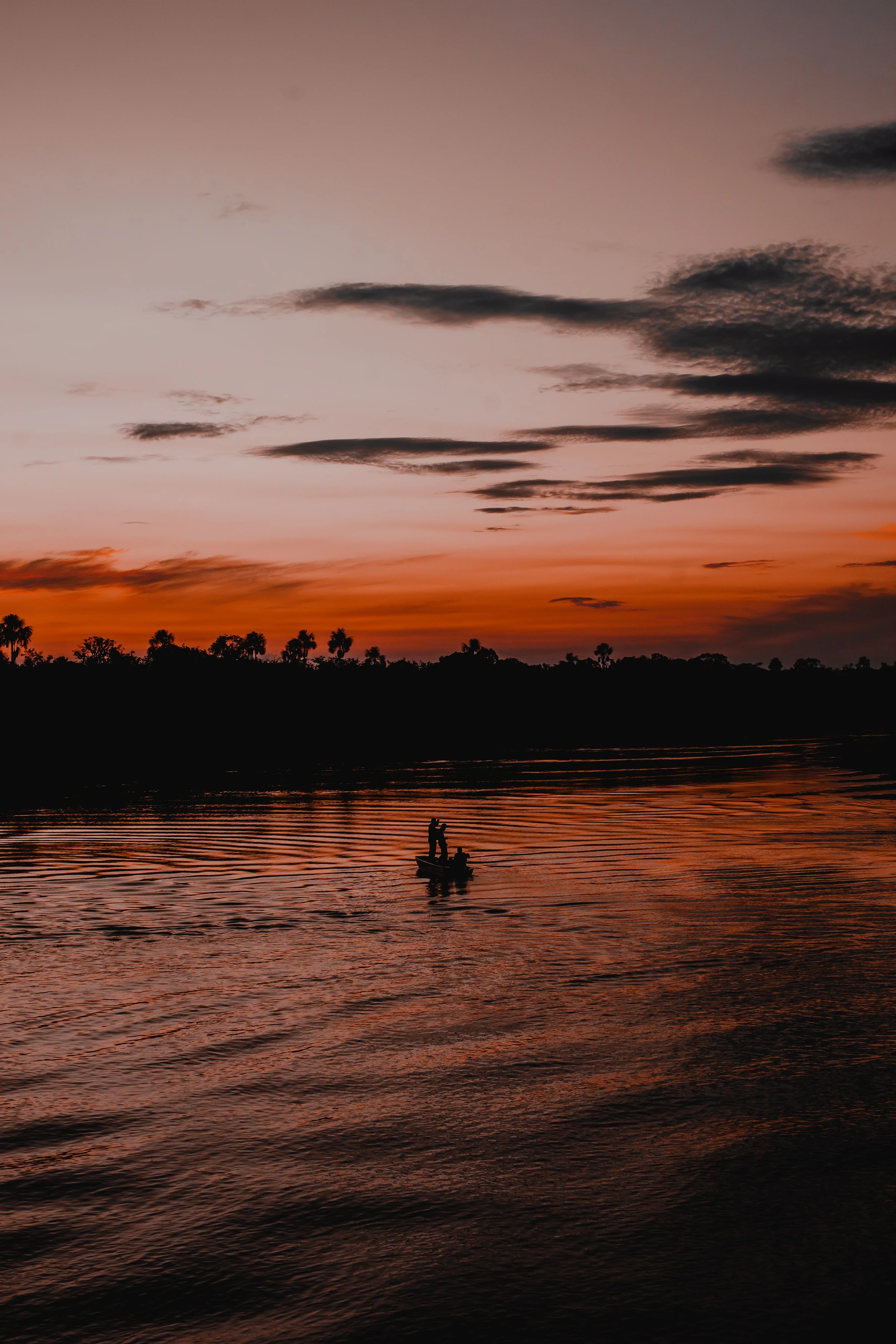 A fishing boat is silhouetted against evening light on the Rio Negro