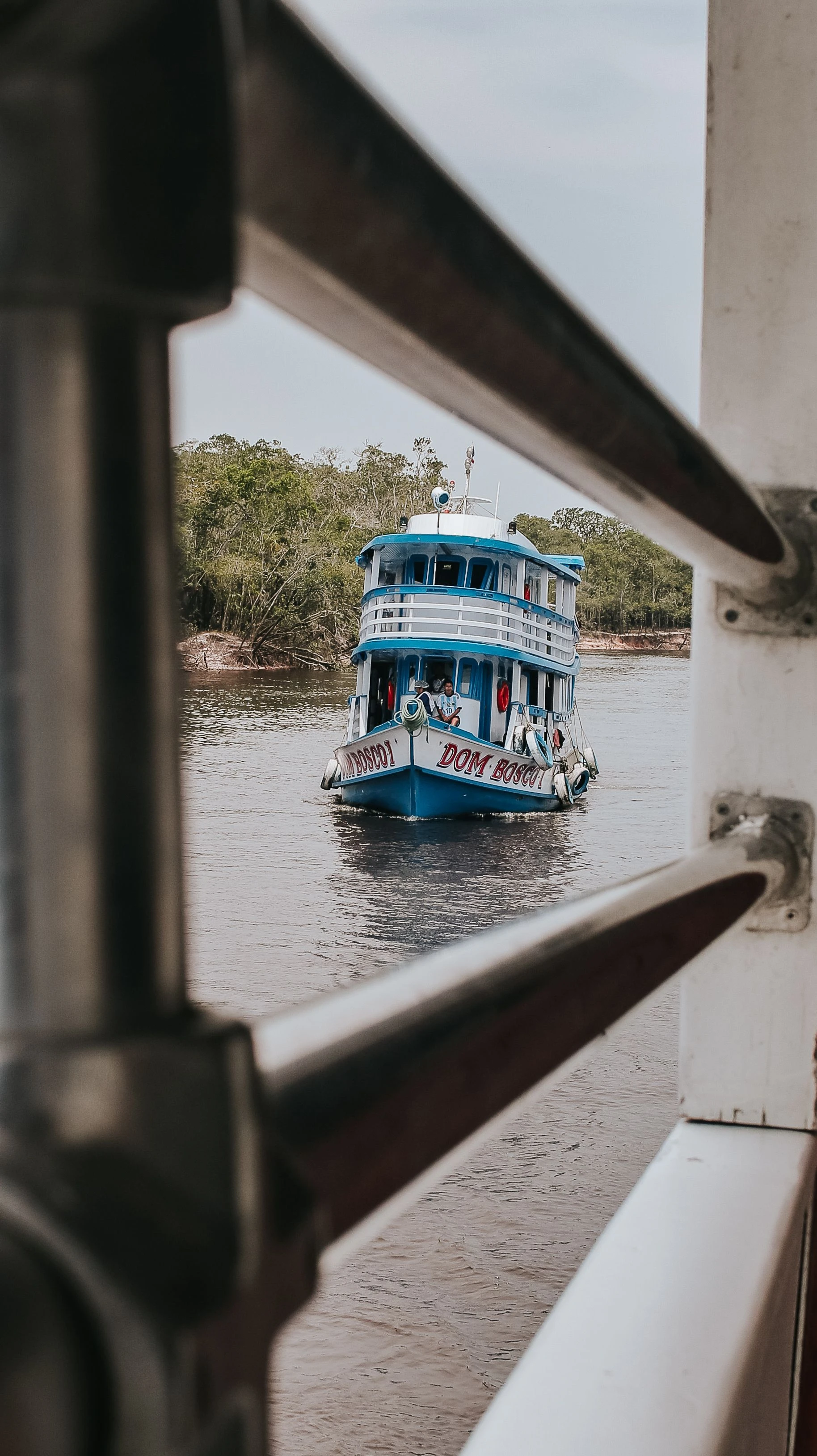 A bright blue riverboat seen through a railing on the Rio Negro in Amazonas.