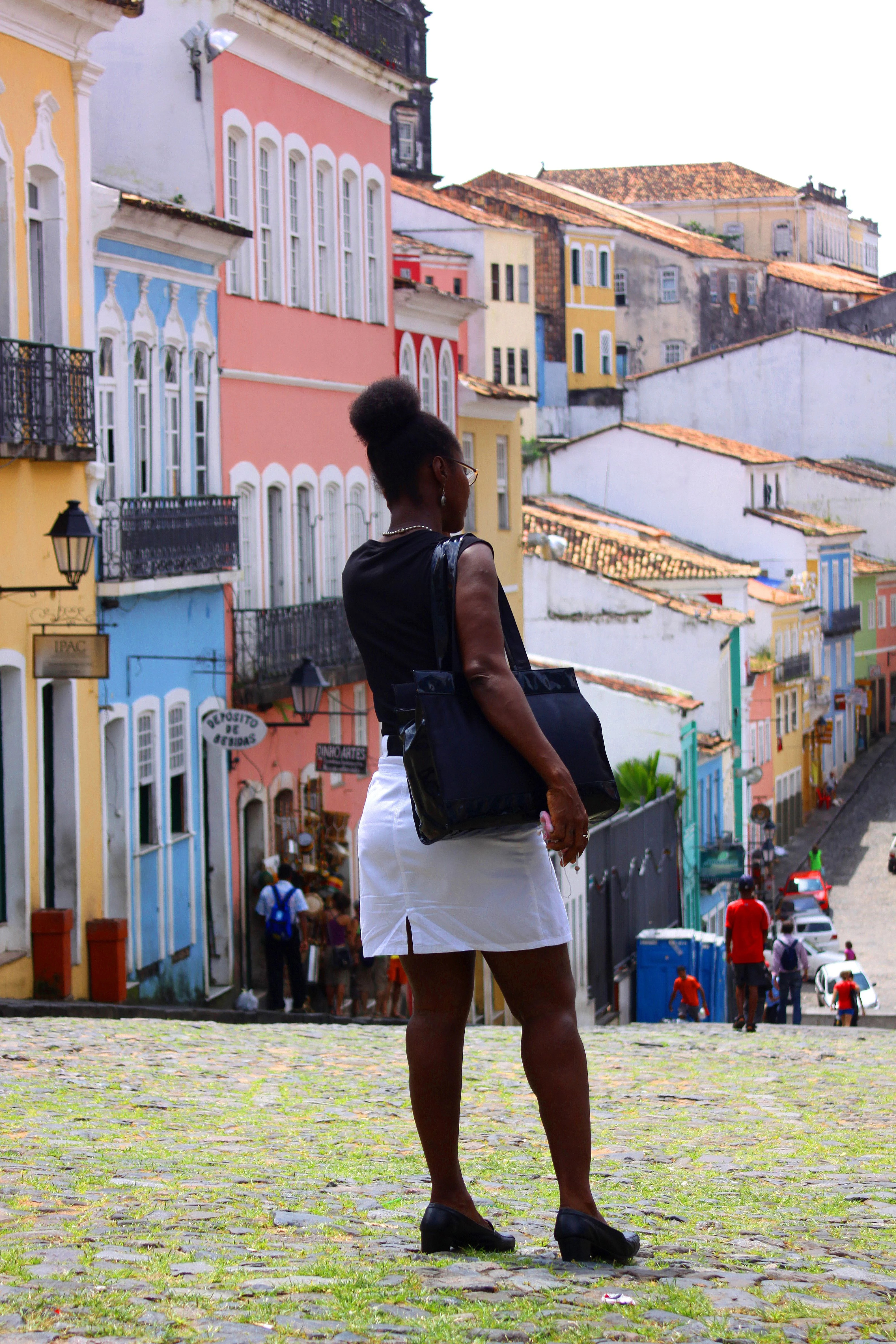 A woman looks over colorful façades and a descending street in Salvador's historic center