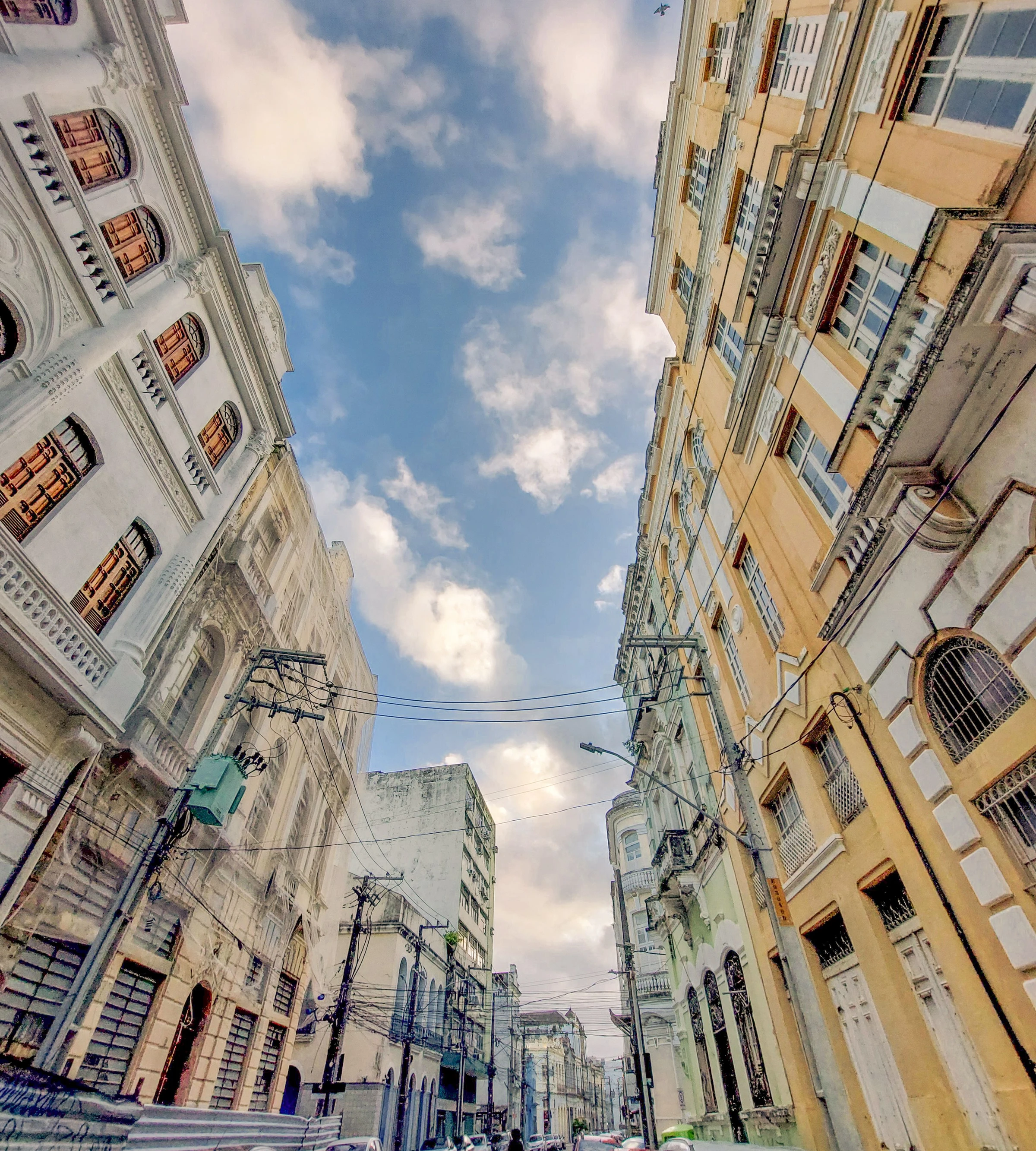 A view looking upward between Recife's historic façades toward a blue sky.