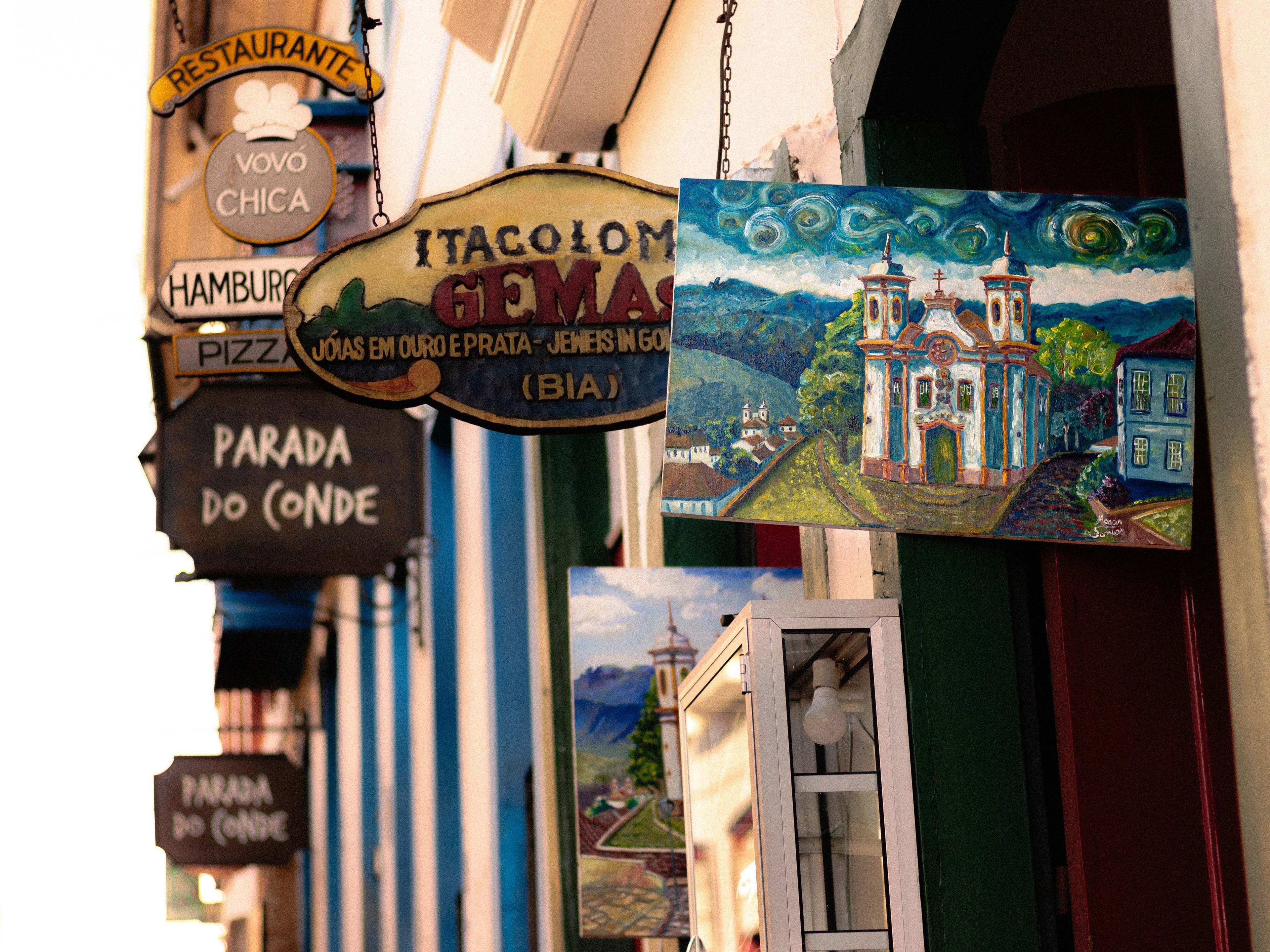Colorful painted artwork and shop signs beside a stone street in Ouro Preto
