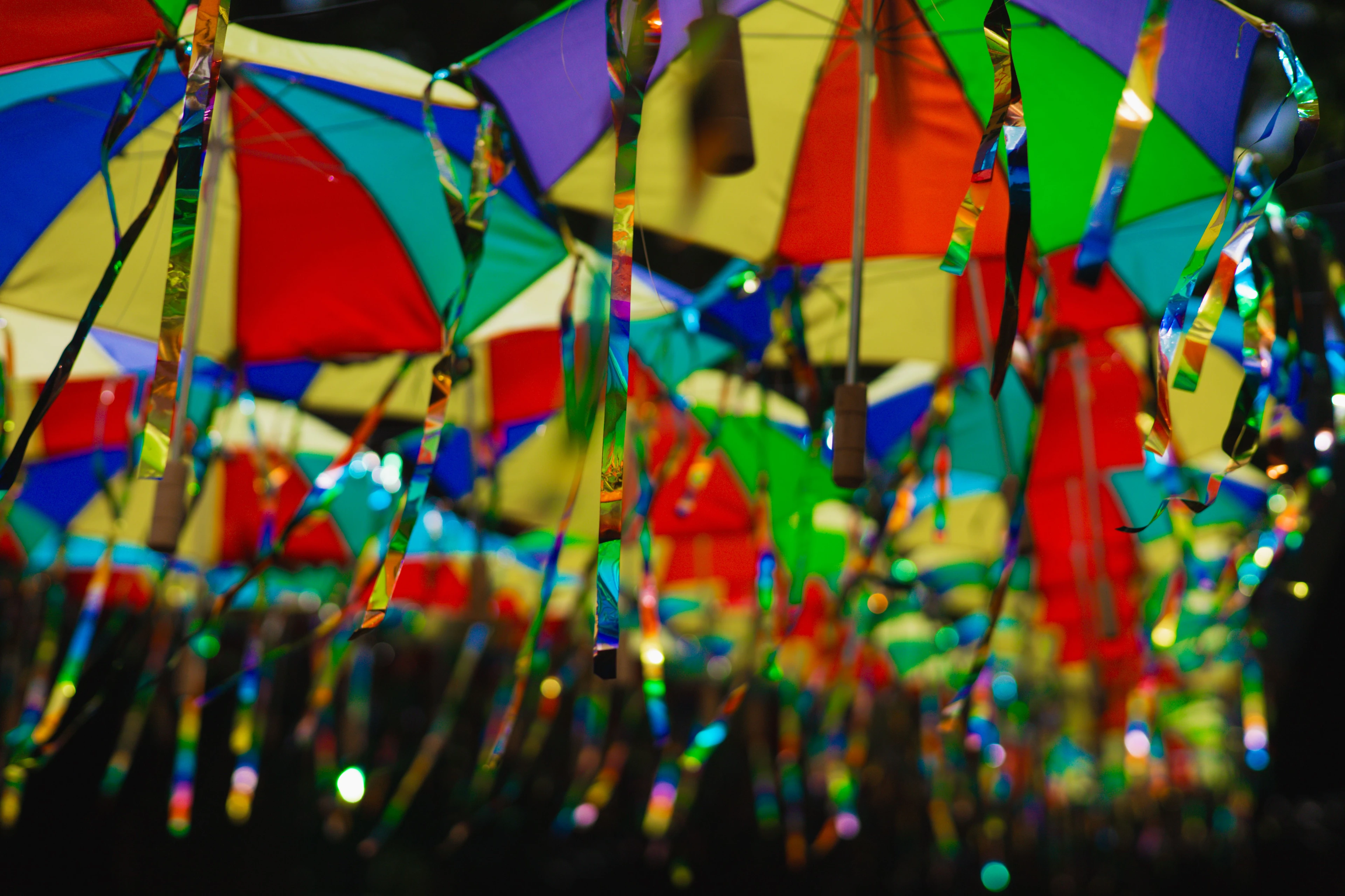 Small frevo umbrellas in vivid red, blue, yellow and green hanging overhead in Olinda