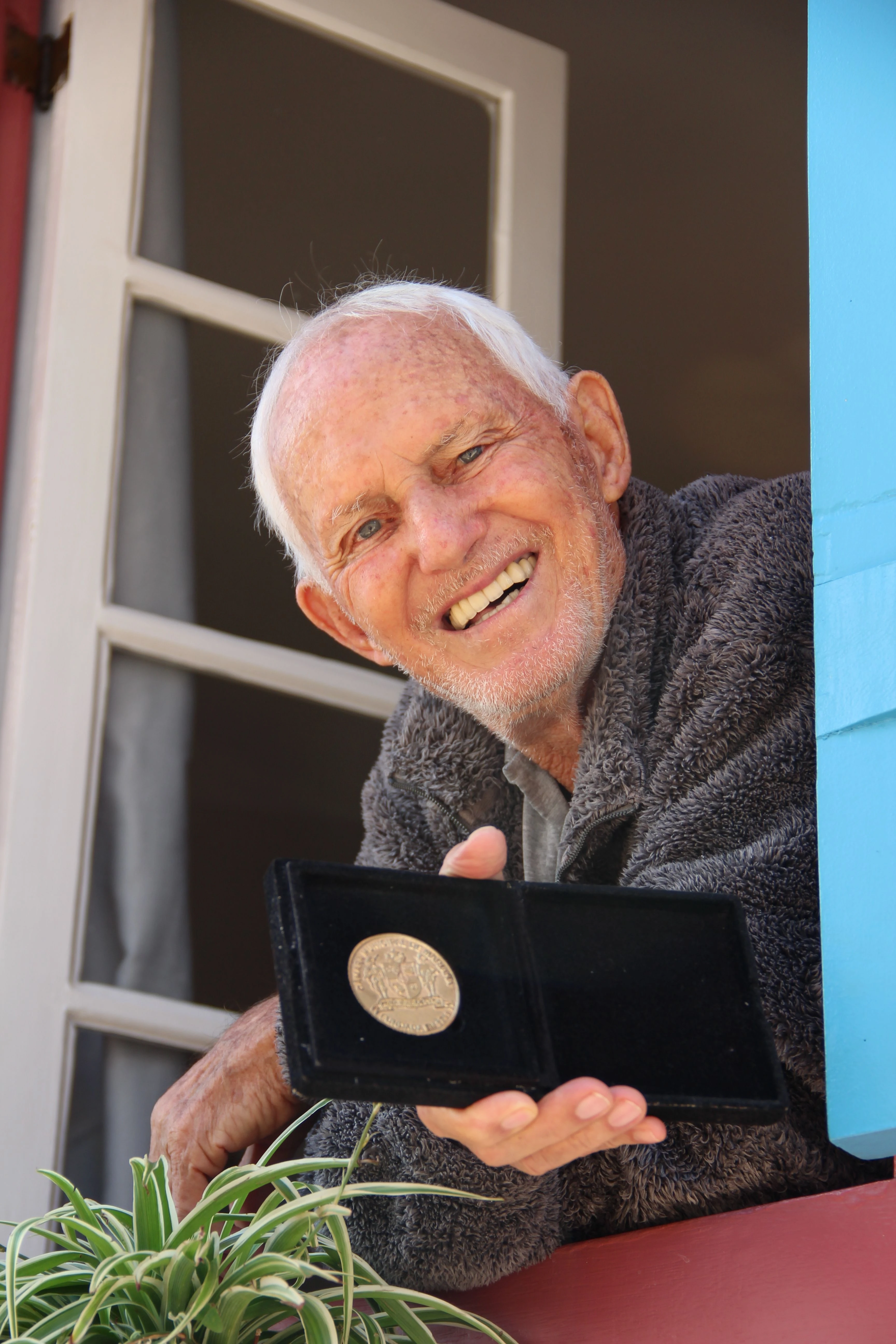 A man leans at a bright blue window in Tiradentes