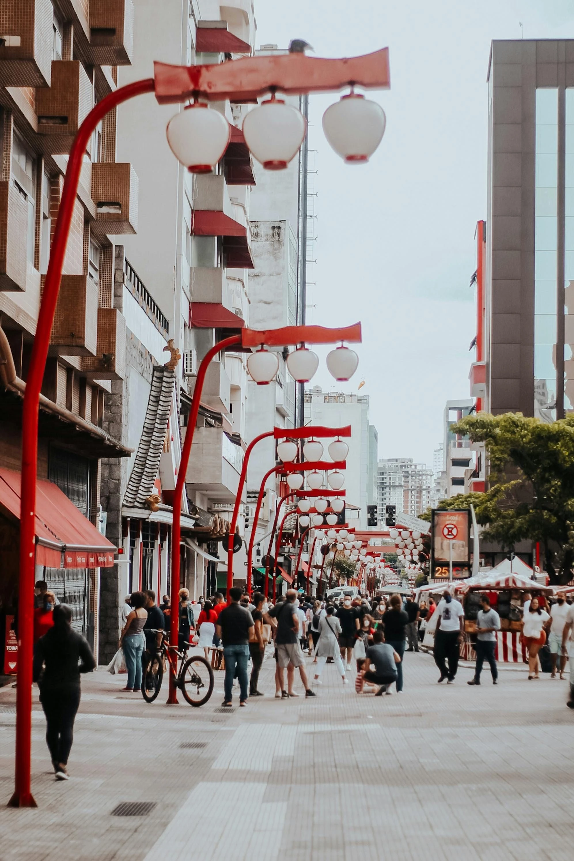Pedestrians beneath red lanterns on a busy Liberdade street