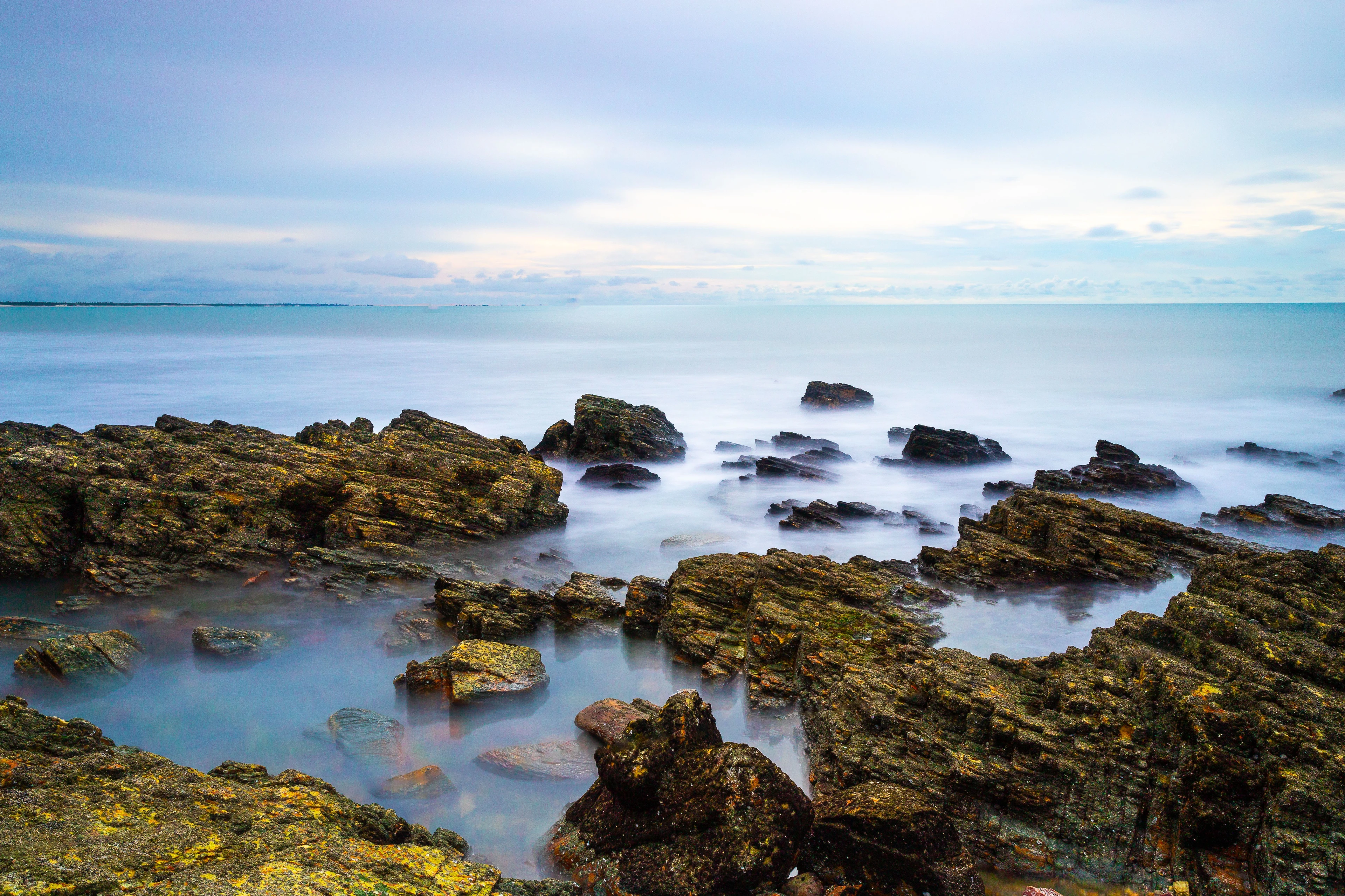 A long exposure captures waves flowing around coastal rocks in Jericoacoara
