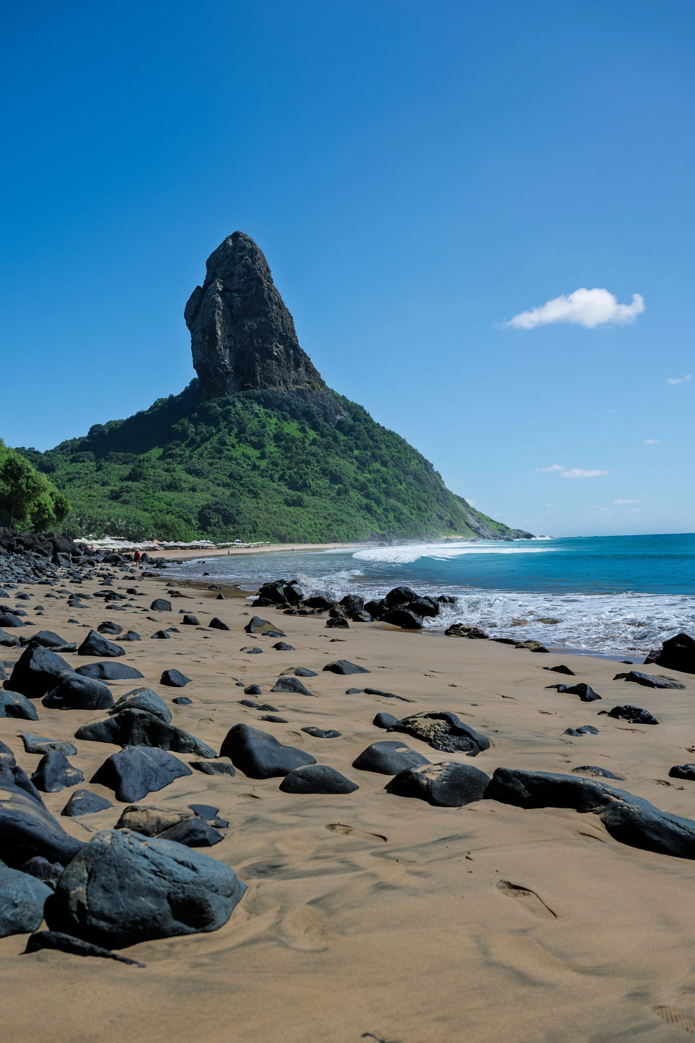 Rounded shoreline boulders frame Fernando de Noronha's steep Morro do Pico