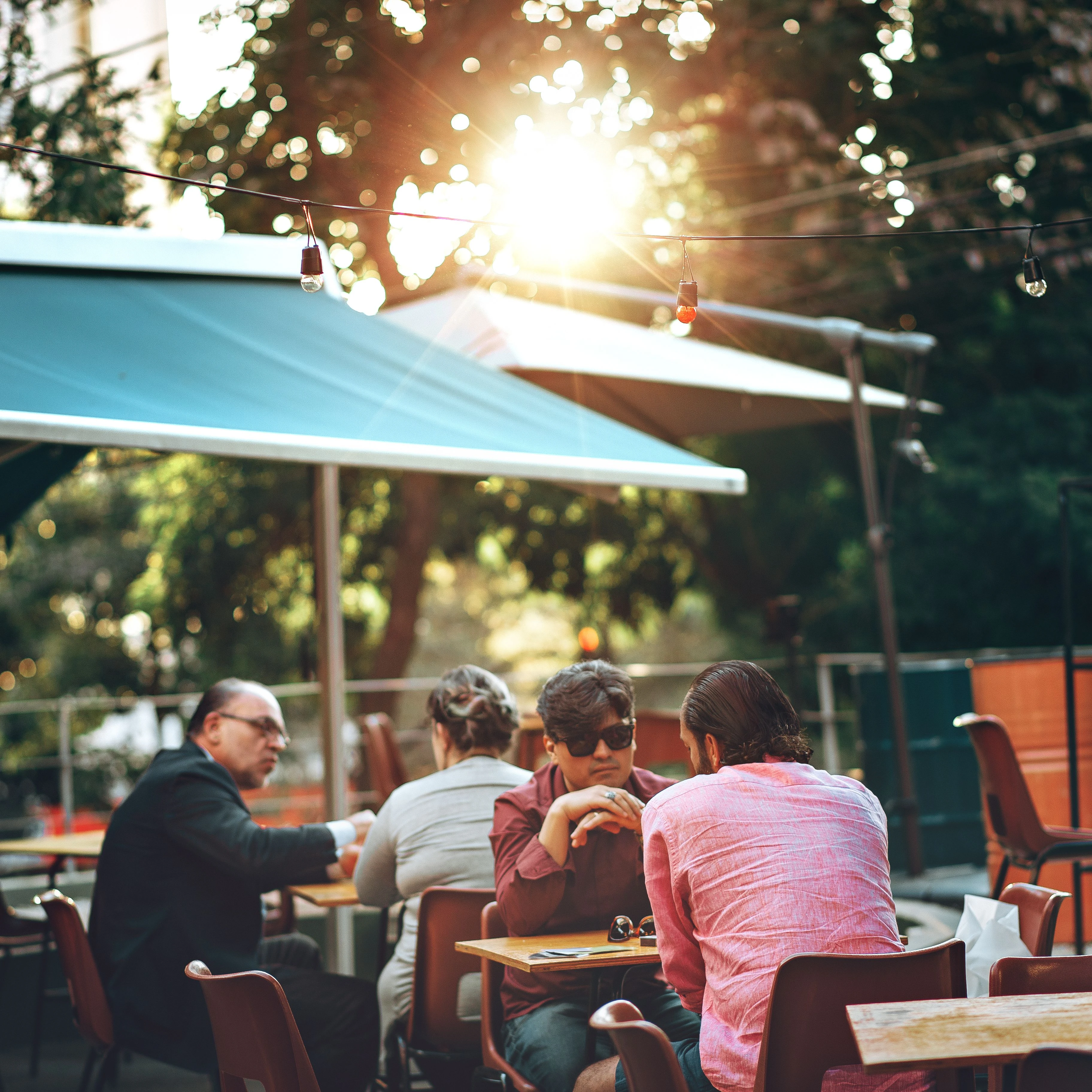 People talk at outdoor café tables in warm afternoon light in Belo Horizonte