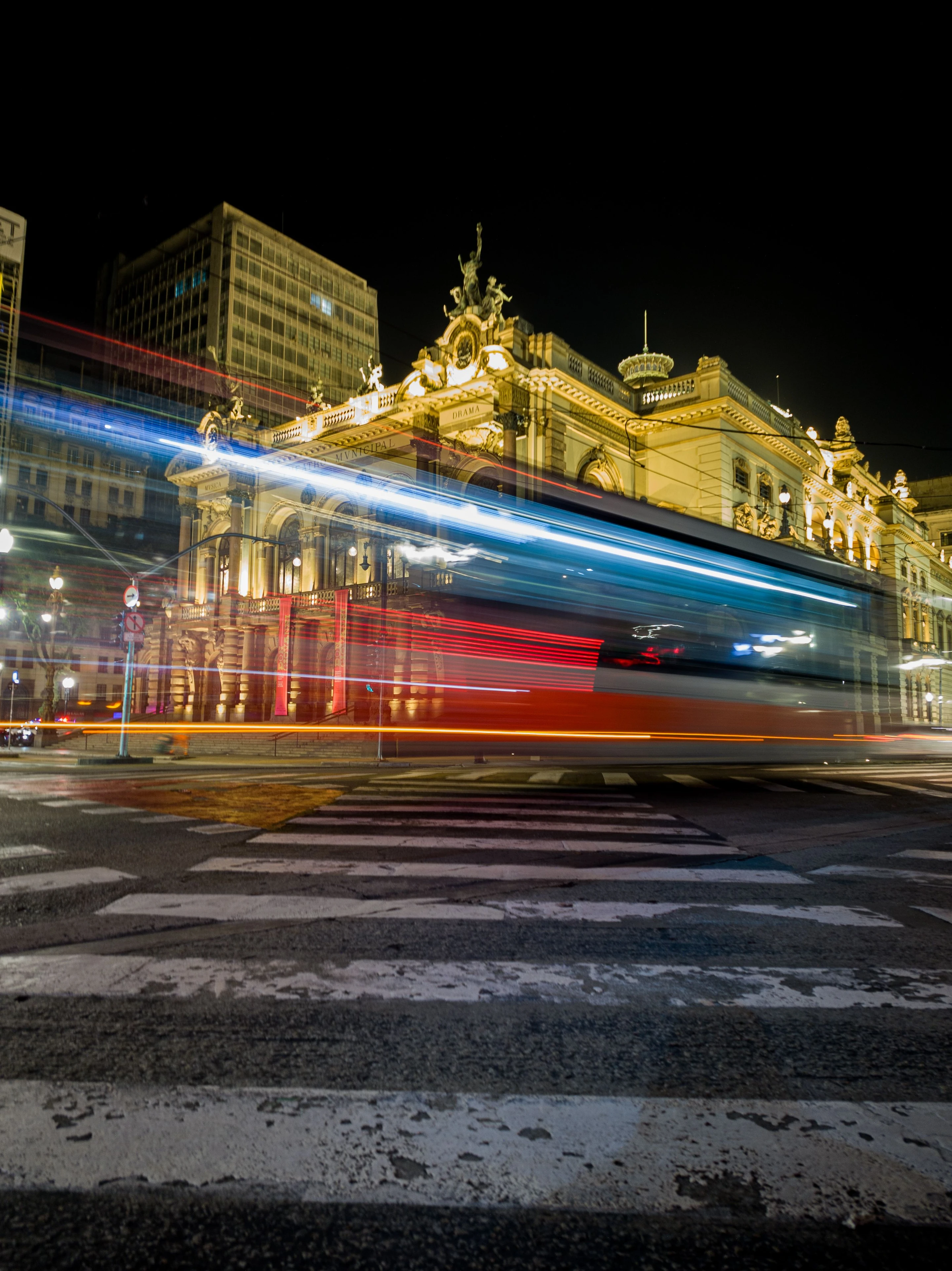 The Theatro Municipal illuminated at night above streaks of traffic light