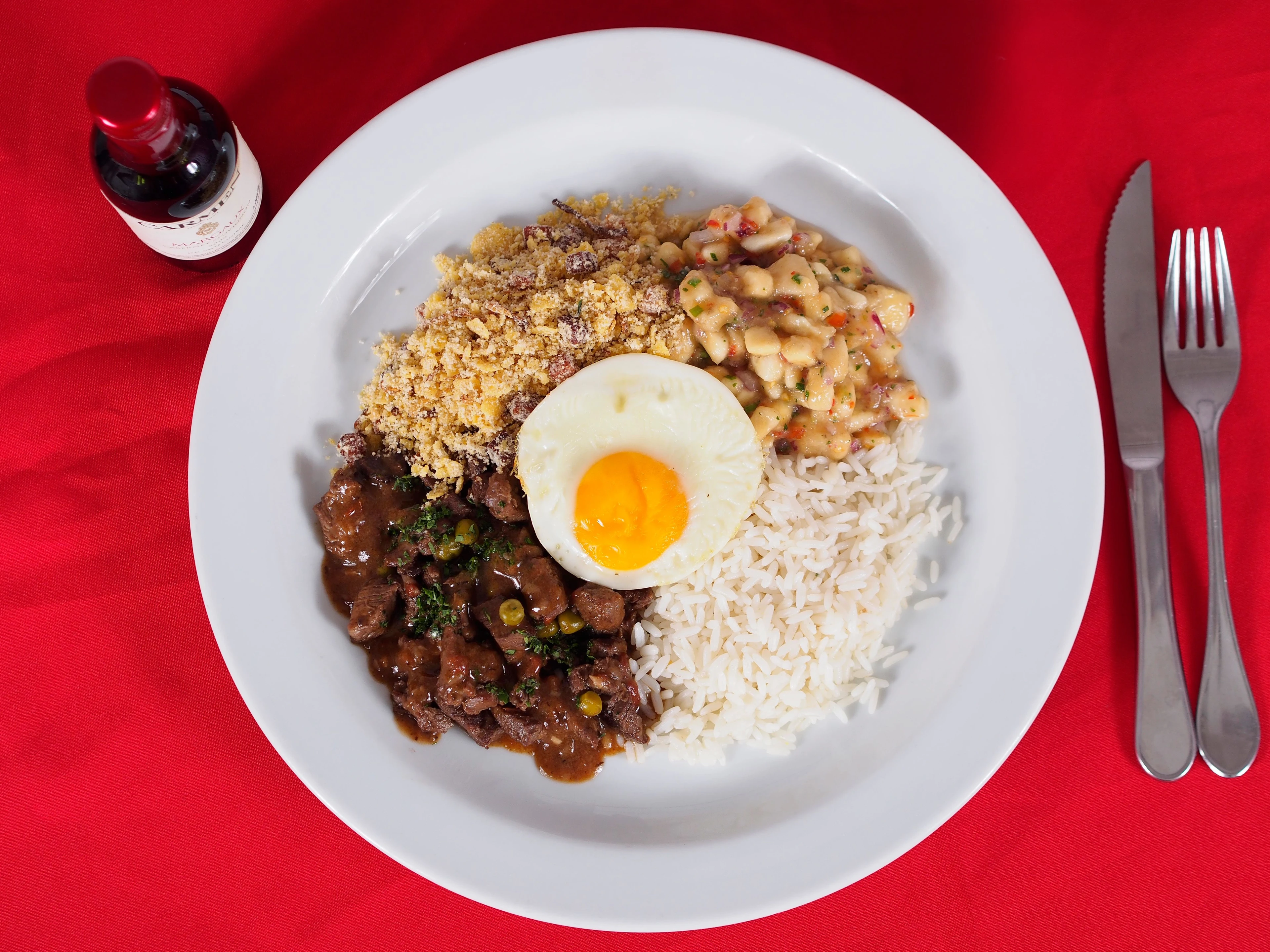 An overhead view of a Brazilian lunch with rice, meat, farofa and a fried egg