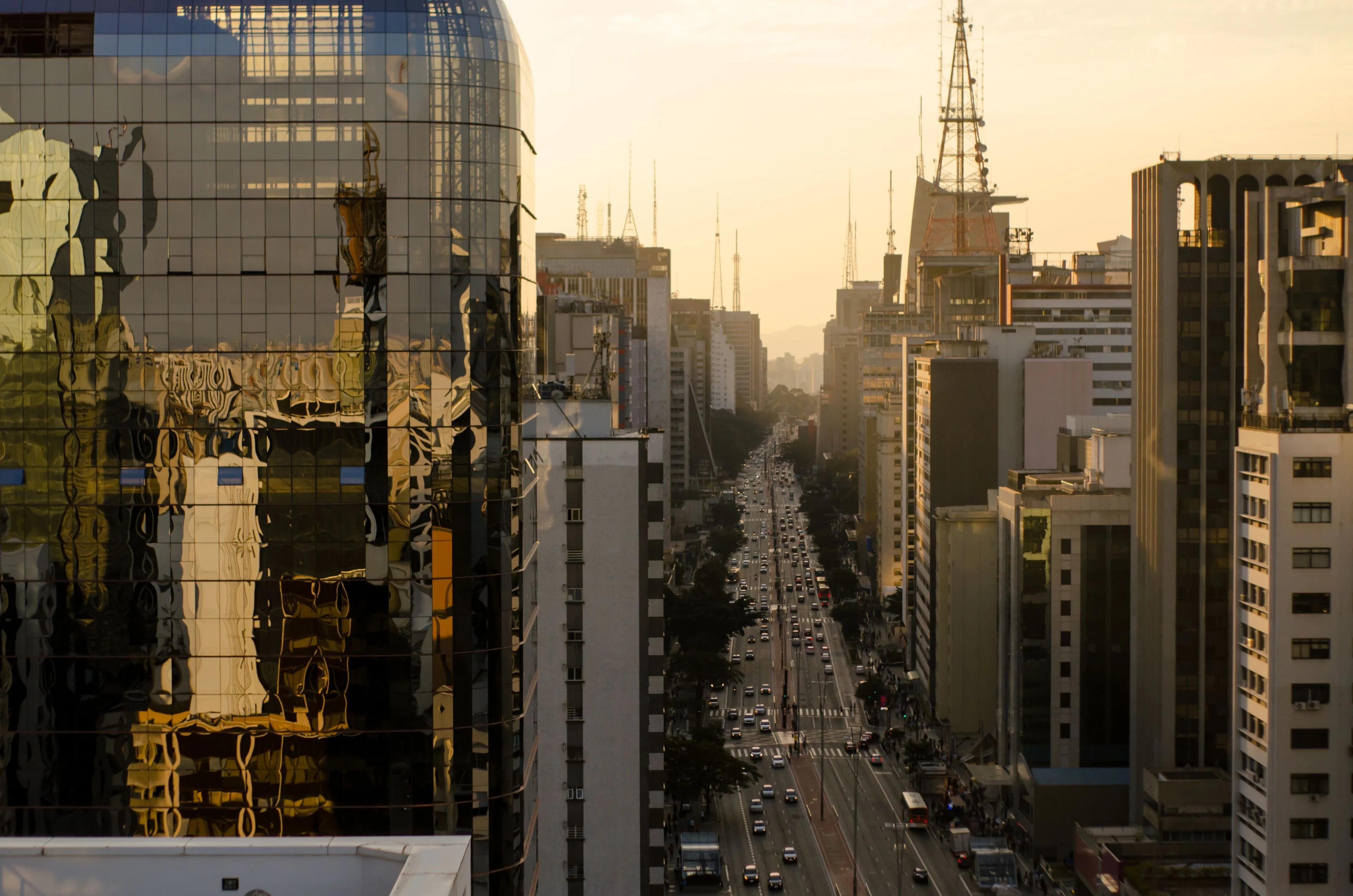 Golden reflections on a glass tower beside the long perspective of Paulista