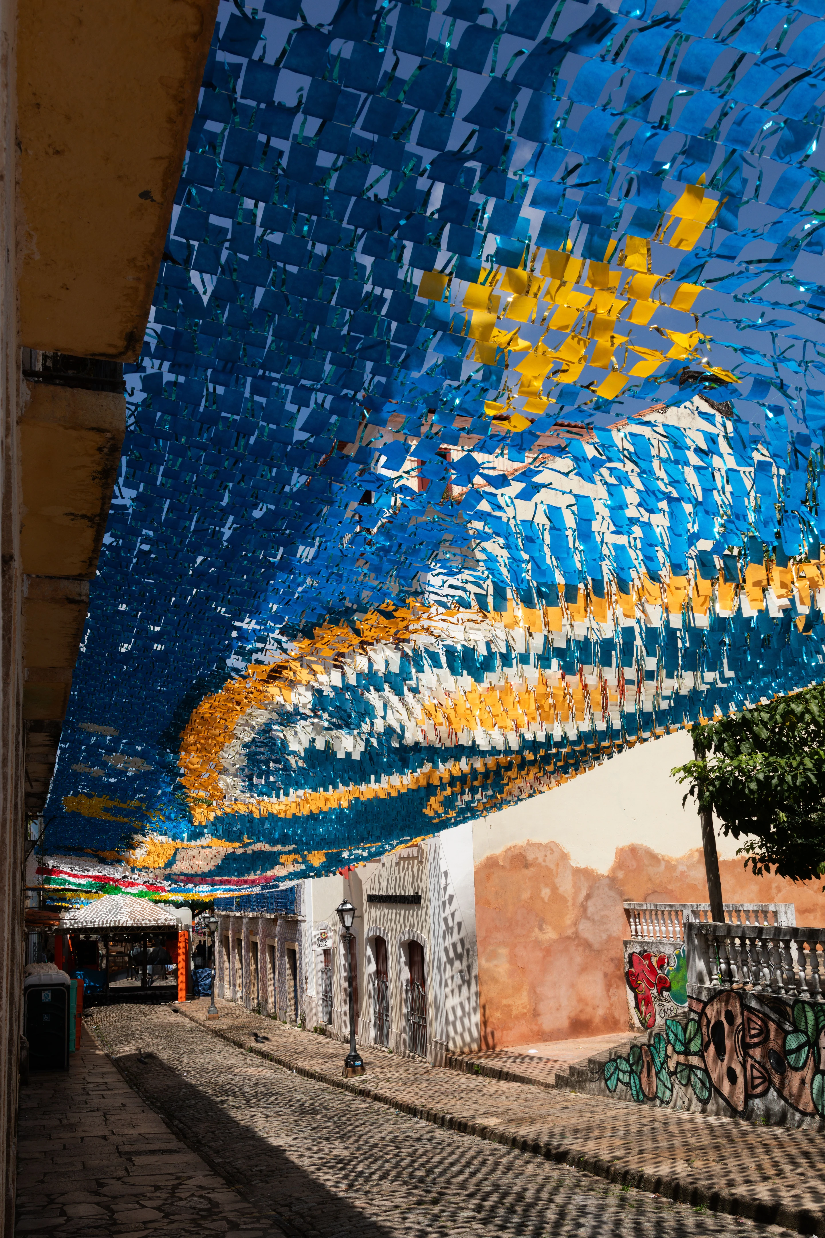Blue and gold festive decorations fill a historic street in São Luís