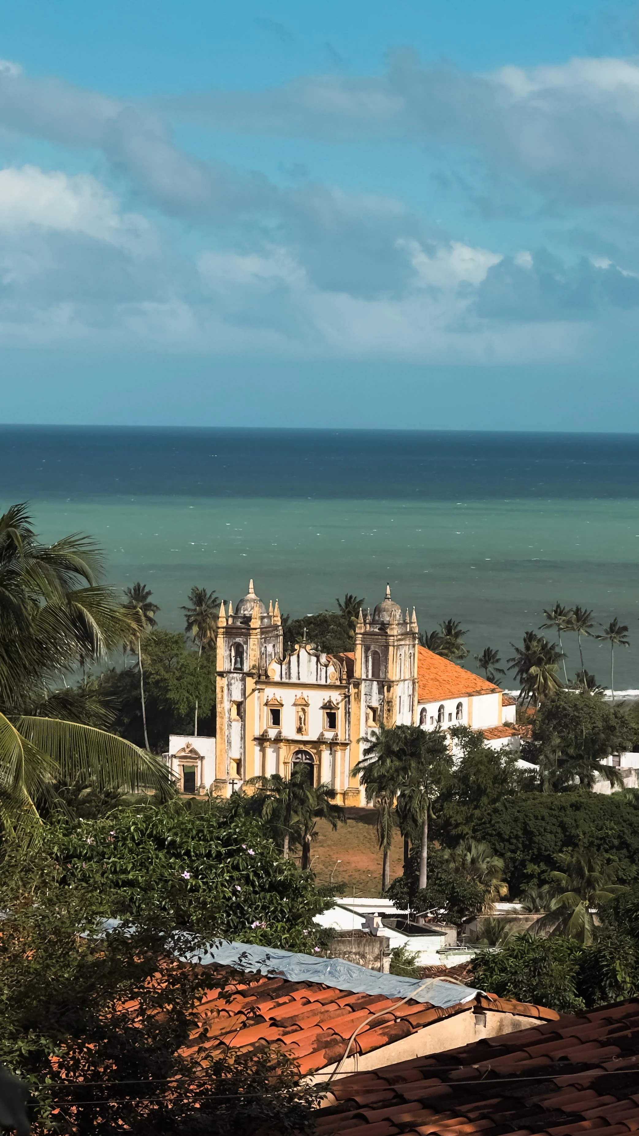 The Carmo church between terracotta roofs and blue ocean in Olinda