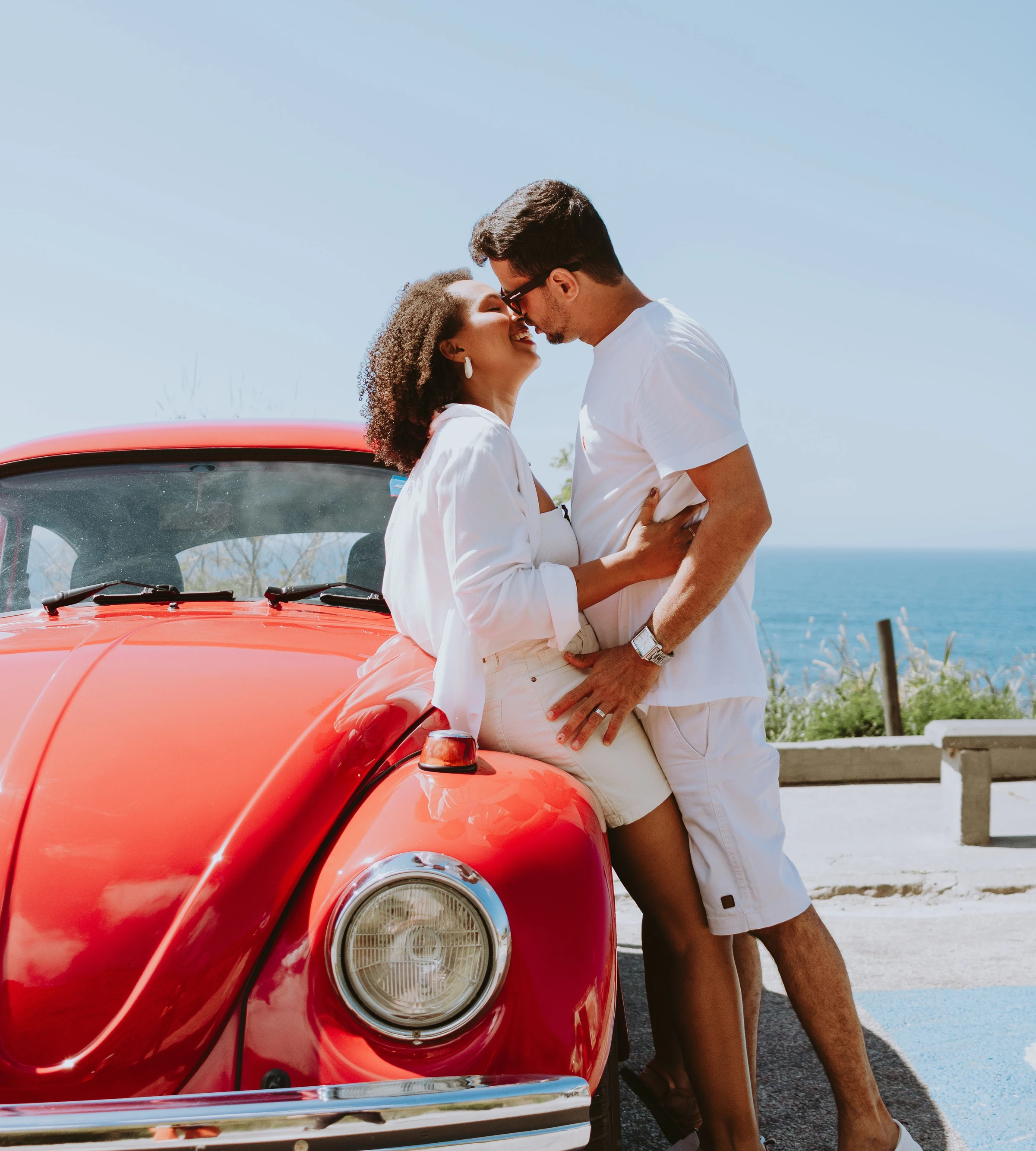 A couple beside a classic red Volkswagen in Rio de Janeiro.