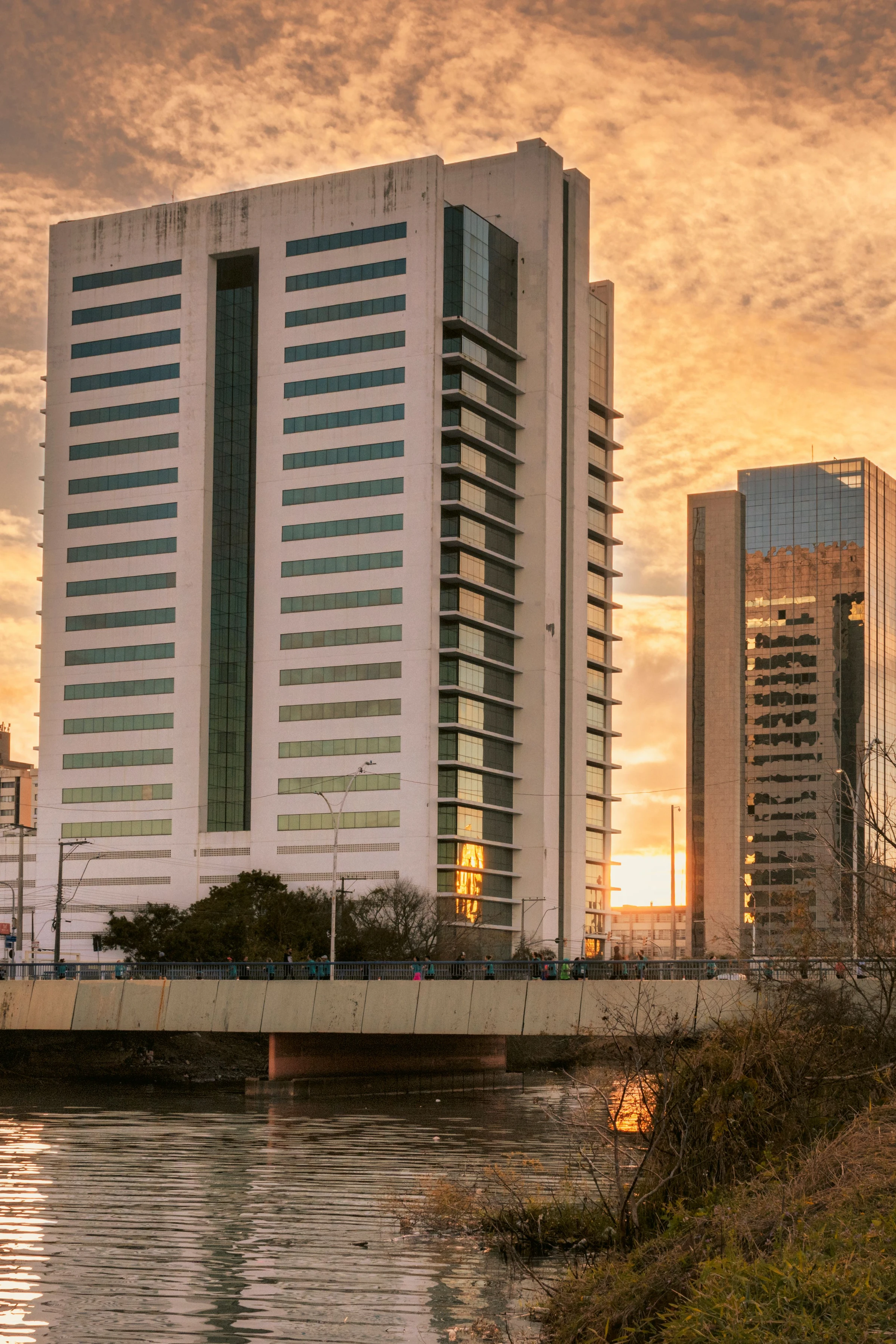 Contemporary city buildings and the waterfront catch the warm light of a dramatic sky in Porto Alegre.