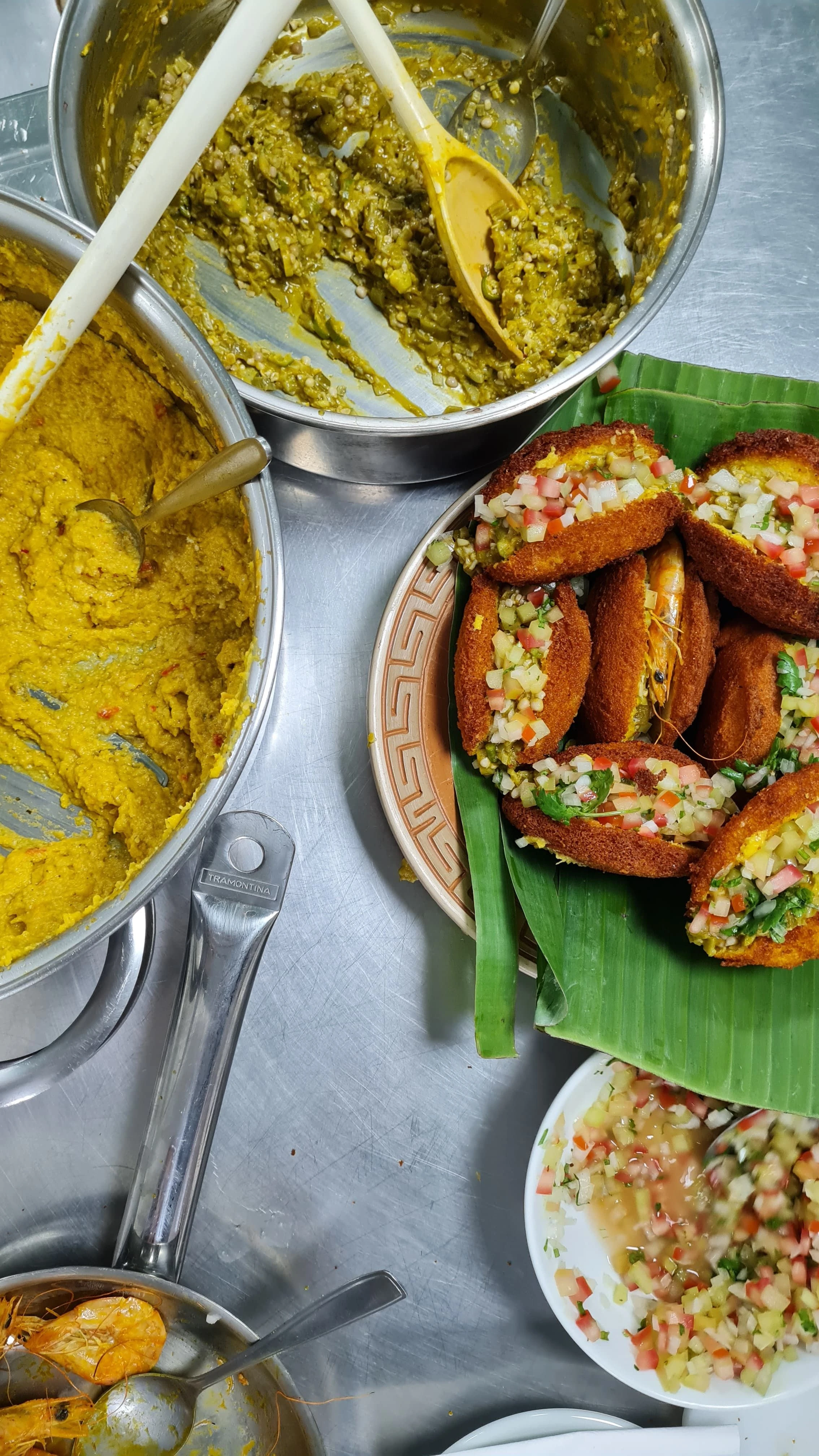 Acarajé, chopped vegetables and prepared accompaniments sit on a kitchen counter