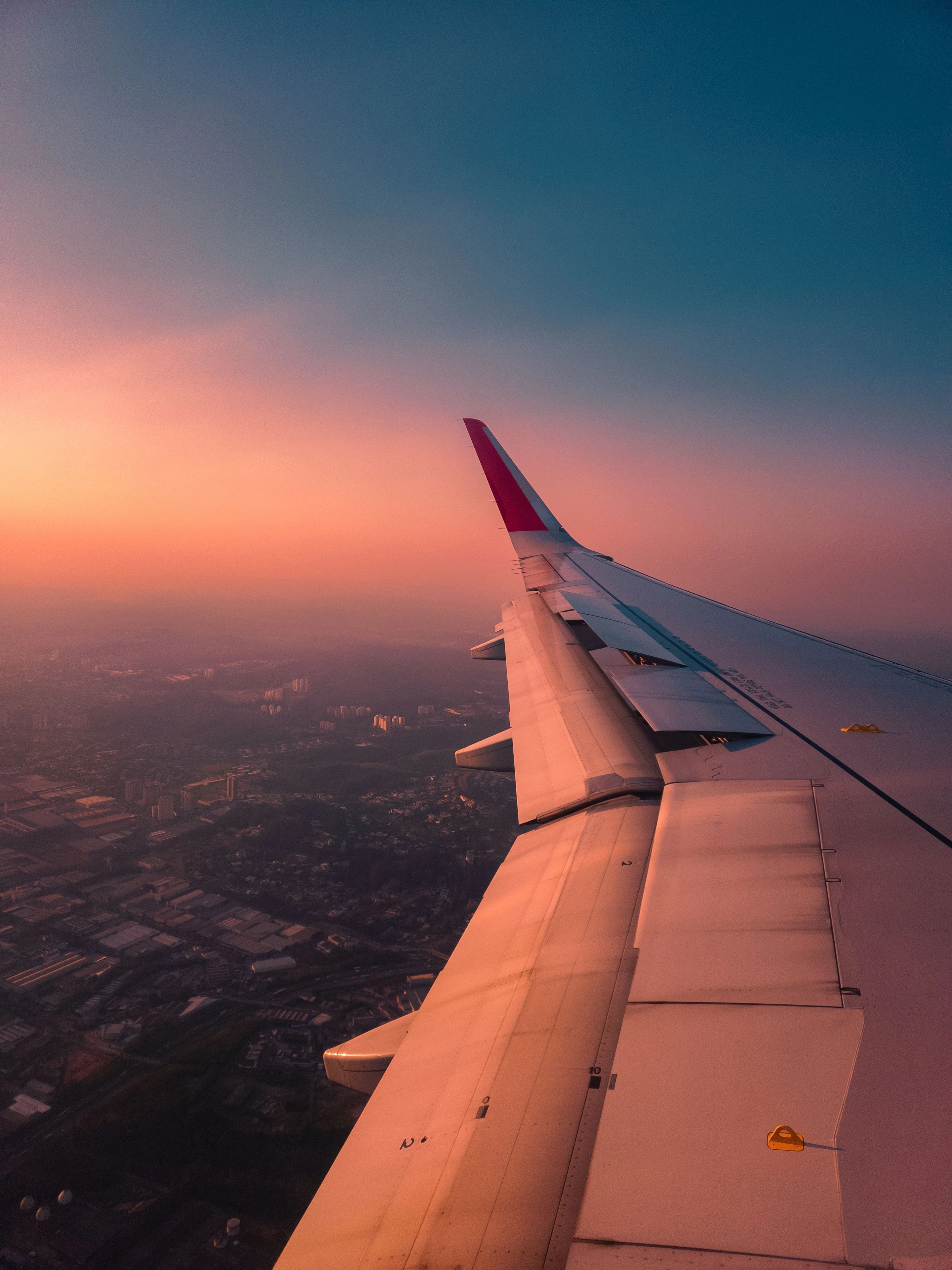 An aircraft wing catching sunset light above São Paulo