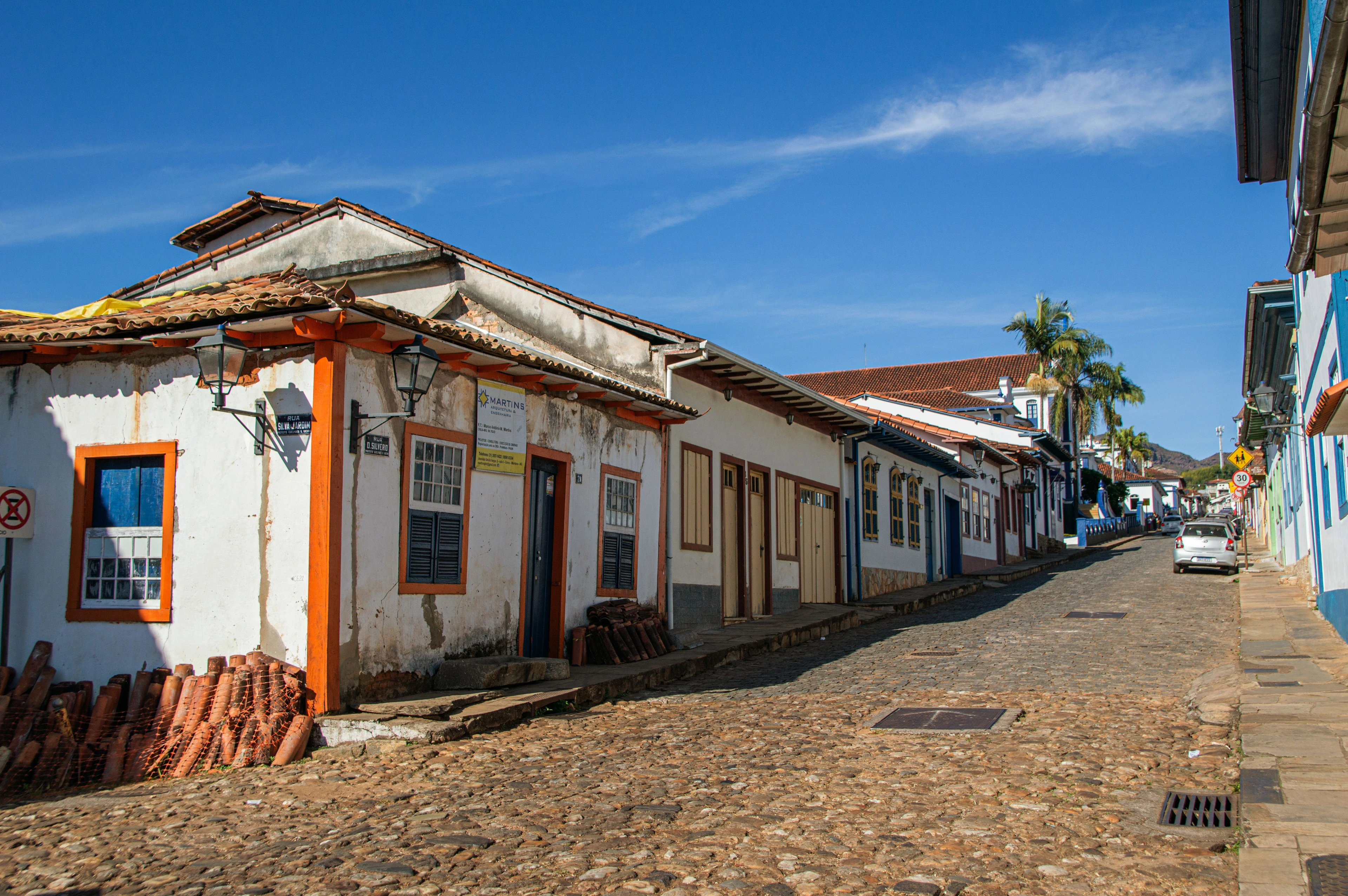A car on a Paraty street lined with bright doors and historic white buildings