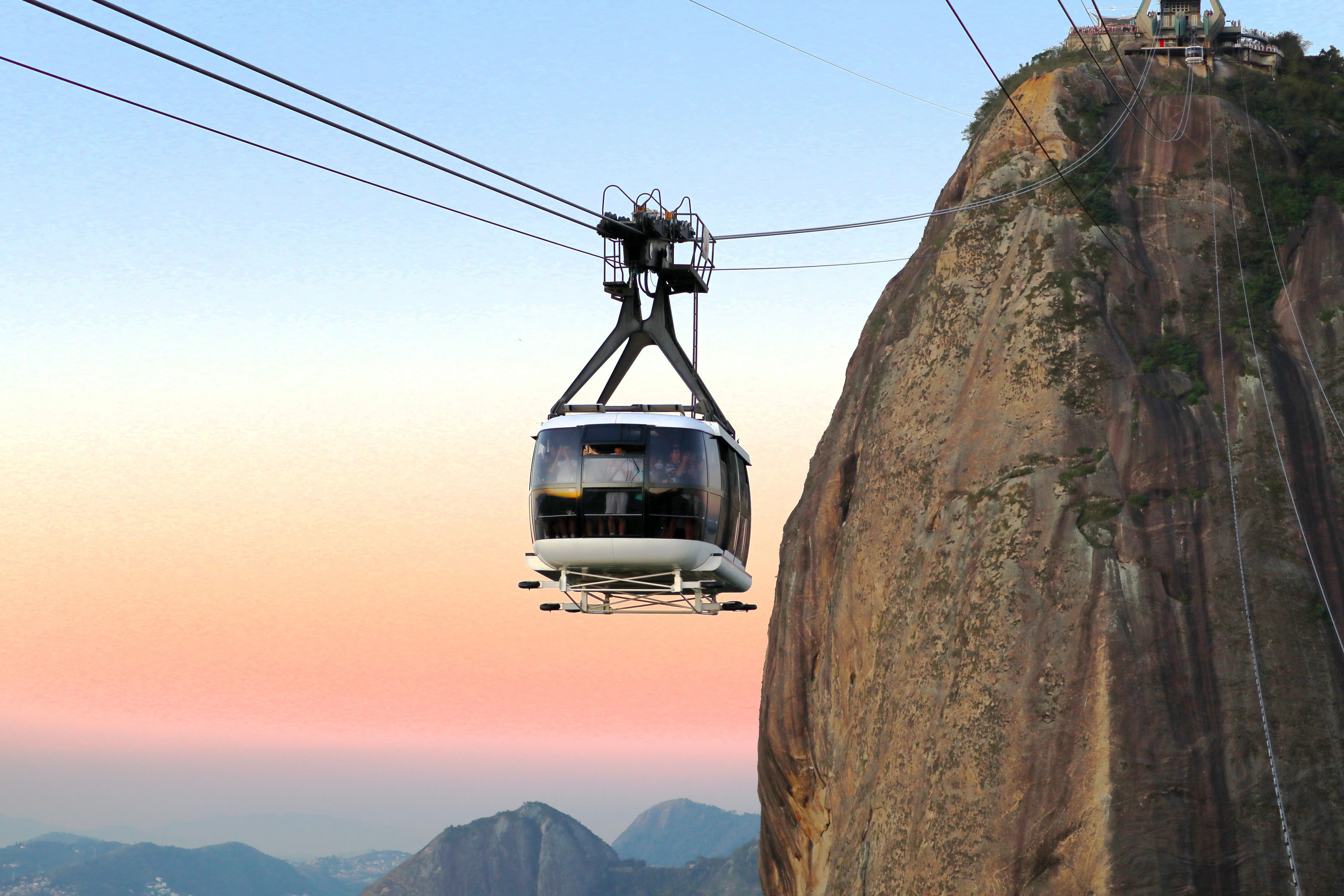 Cable car suspended beside Sugarloaf’s steep rock face against a pastel sunset sky