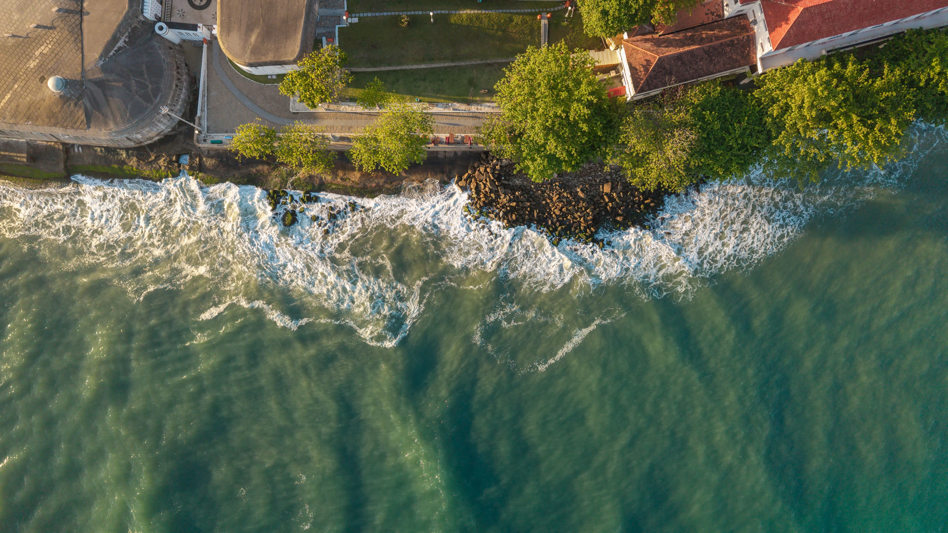 Atlantic waves breaking below waterfront architecture in warm afternoon light, seen directly from above.
