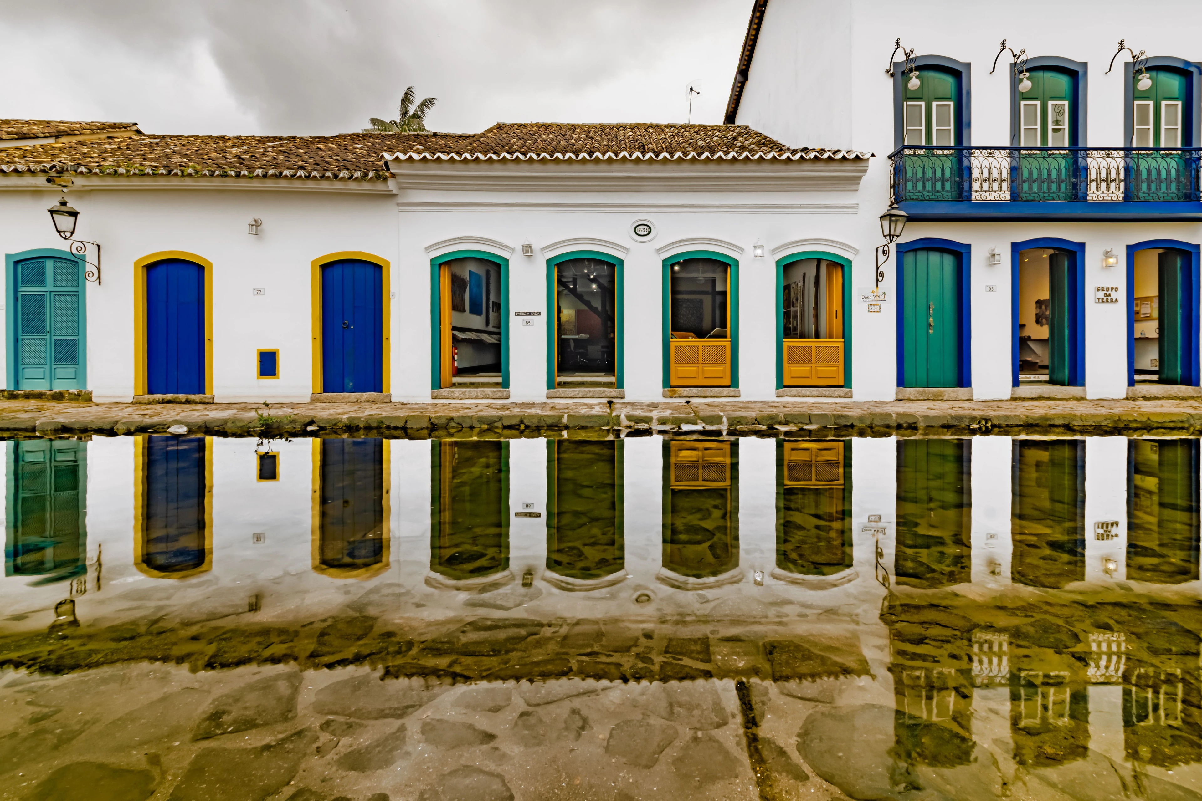 Blue, yellow and turquoise doors of Paraty’s historic buildings reflected in water