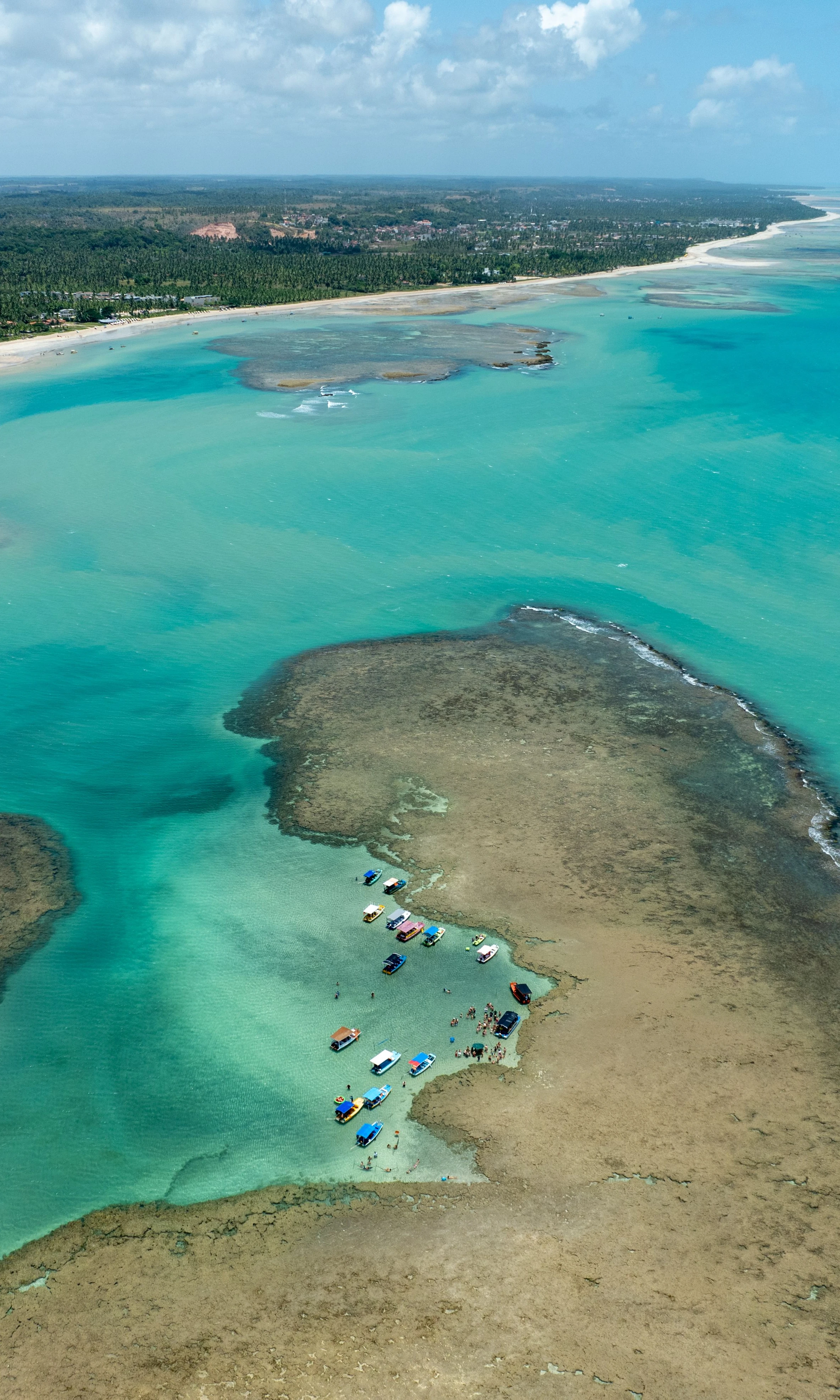 Small boats gather near a reef off the turquoise coastline of São Miguel dos Milagres.
