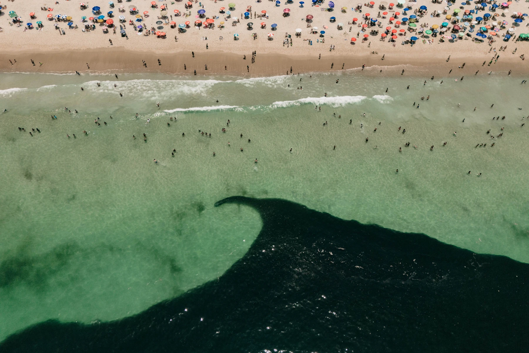 Beachgoers, umbrellas and waves seen from above · Rio de Janeiro