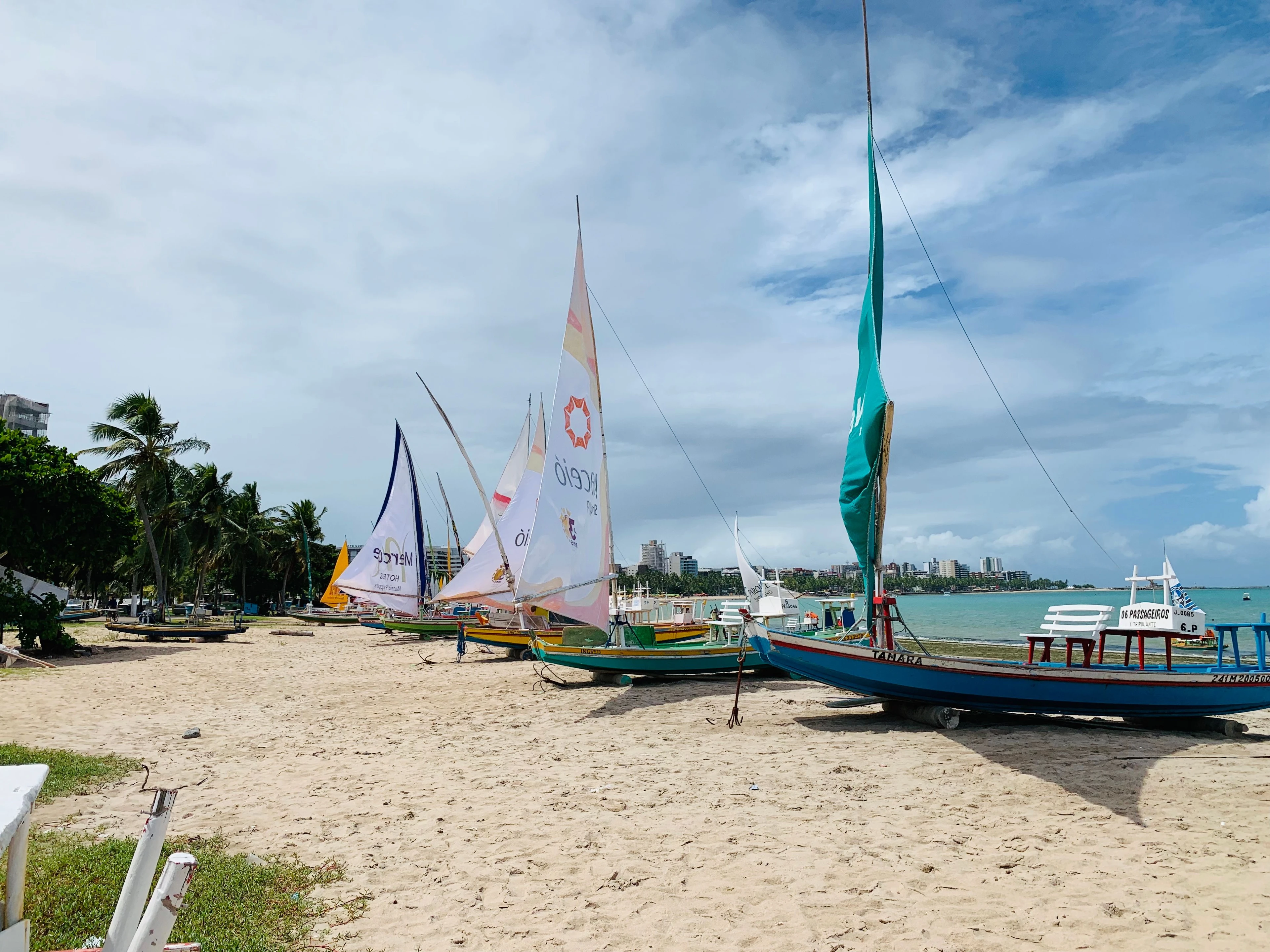 Colorful jangadas with tall sails resting on the beach at Pajuçara in Maceió